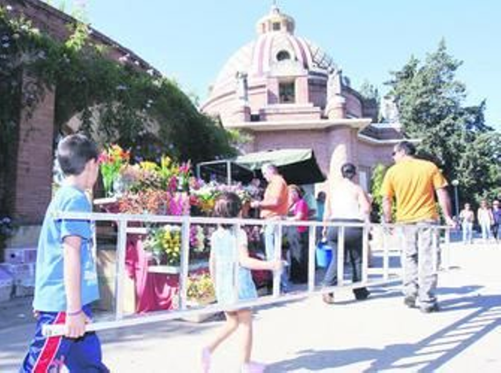 Dos niños ayudan a su padre a cargar con una escalera por el acceso al cementerio de Jerez.