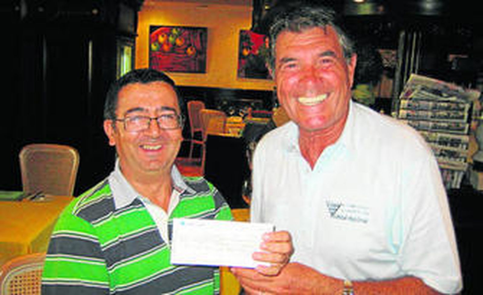 Antonio Arias entrega al director de la peña, Juan Rueda, el cheque con el premio de la quiniela.