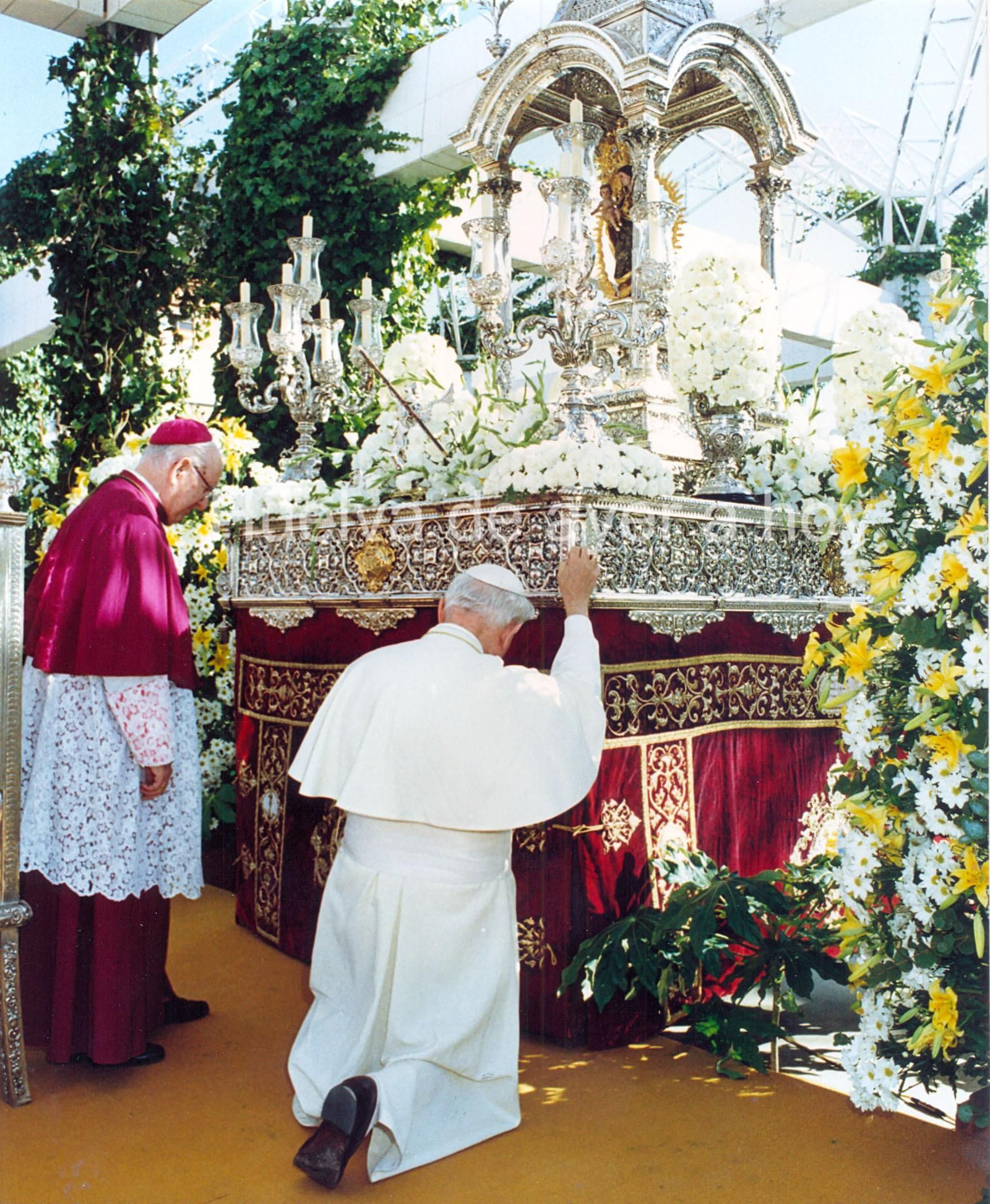 San Juan Pablo II arrodillado se agarra al paso de la Virgen de la Cinta, acompañado del obispo Rafael González Moralejo.