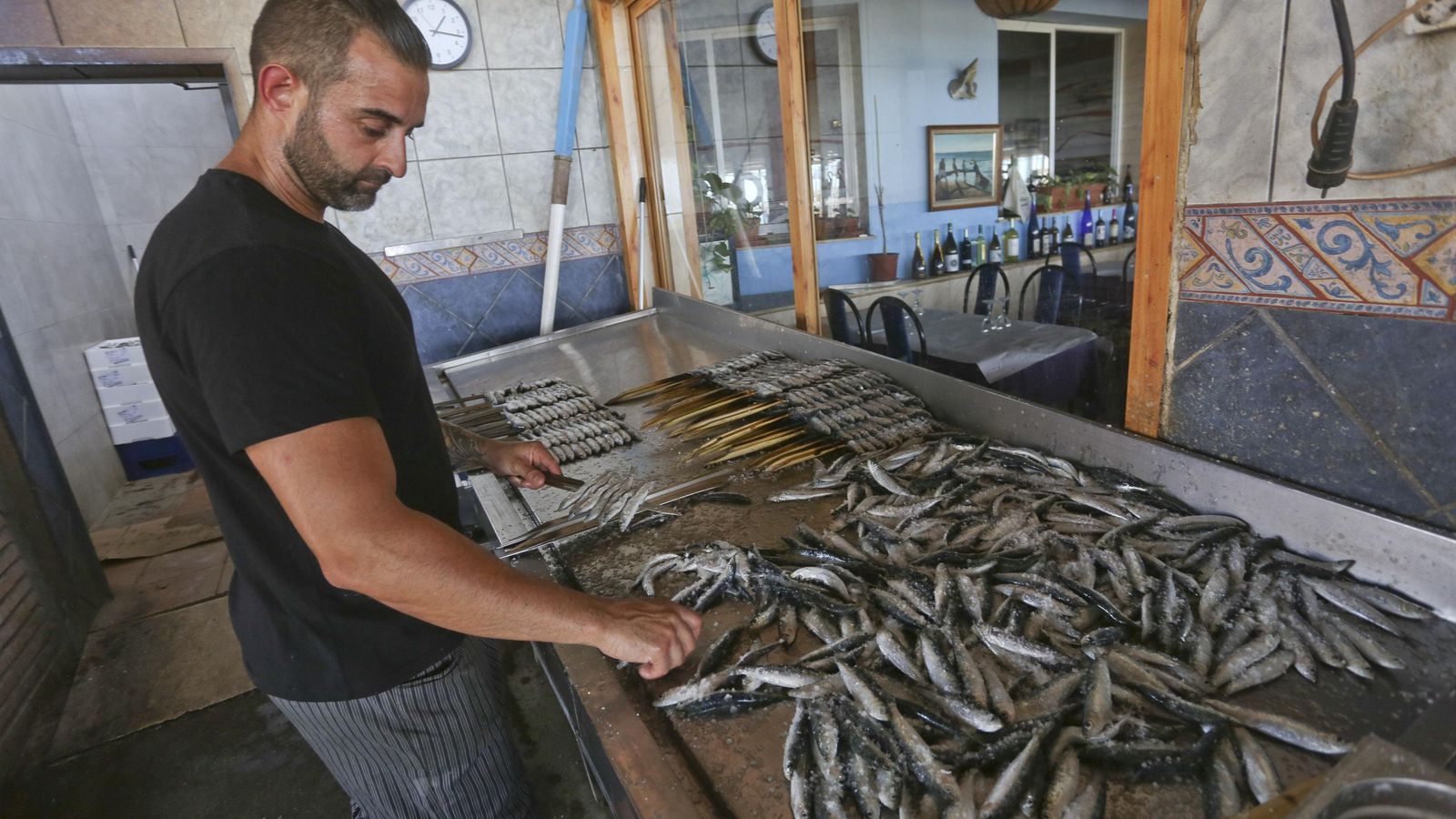 Un trabajador de El Tintero trincha sardinas en un caña para hacer un espeto Un trabajador de El Tintero trincha sardinas en un caña para hacer un espeto