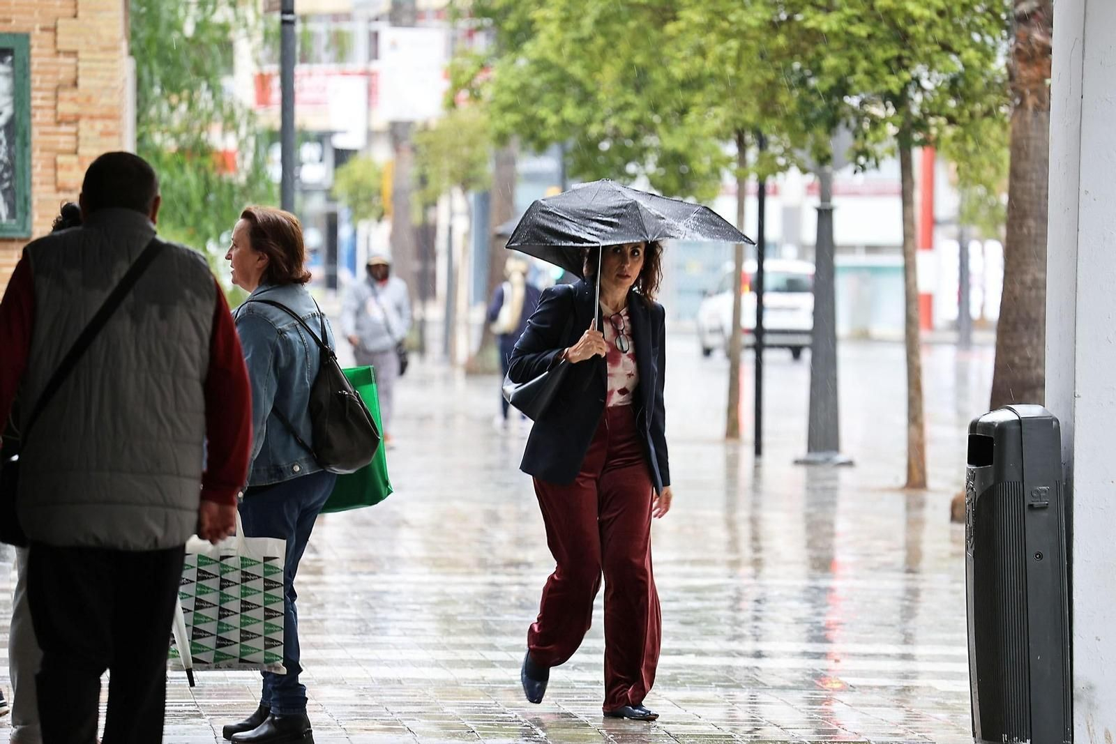 Una mujer se protege de la lluvia con su paraguas en Huelva.