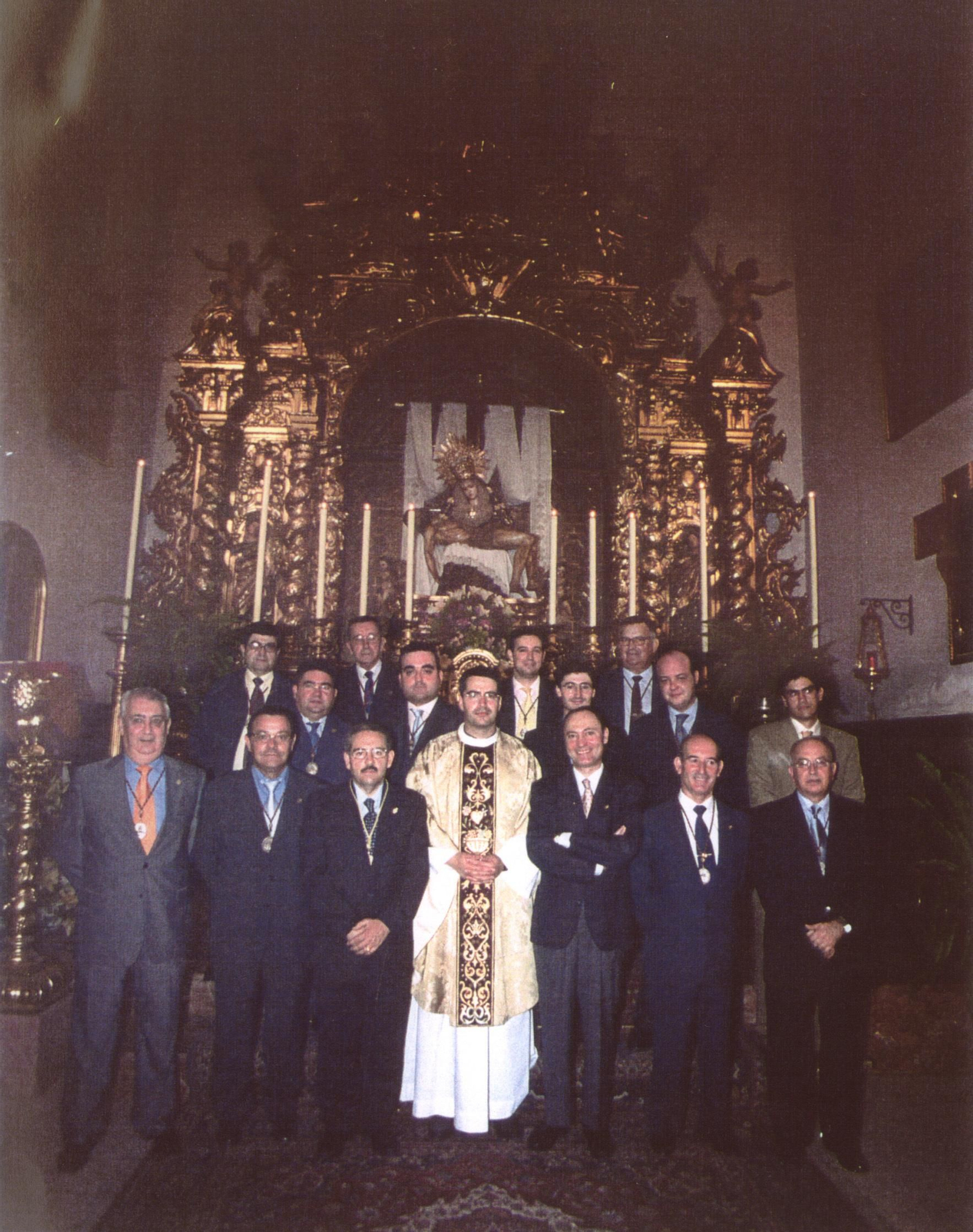 Varios cofrades ante el altar con la Piedad de los Servitas.