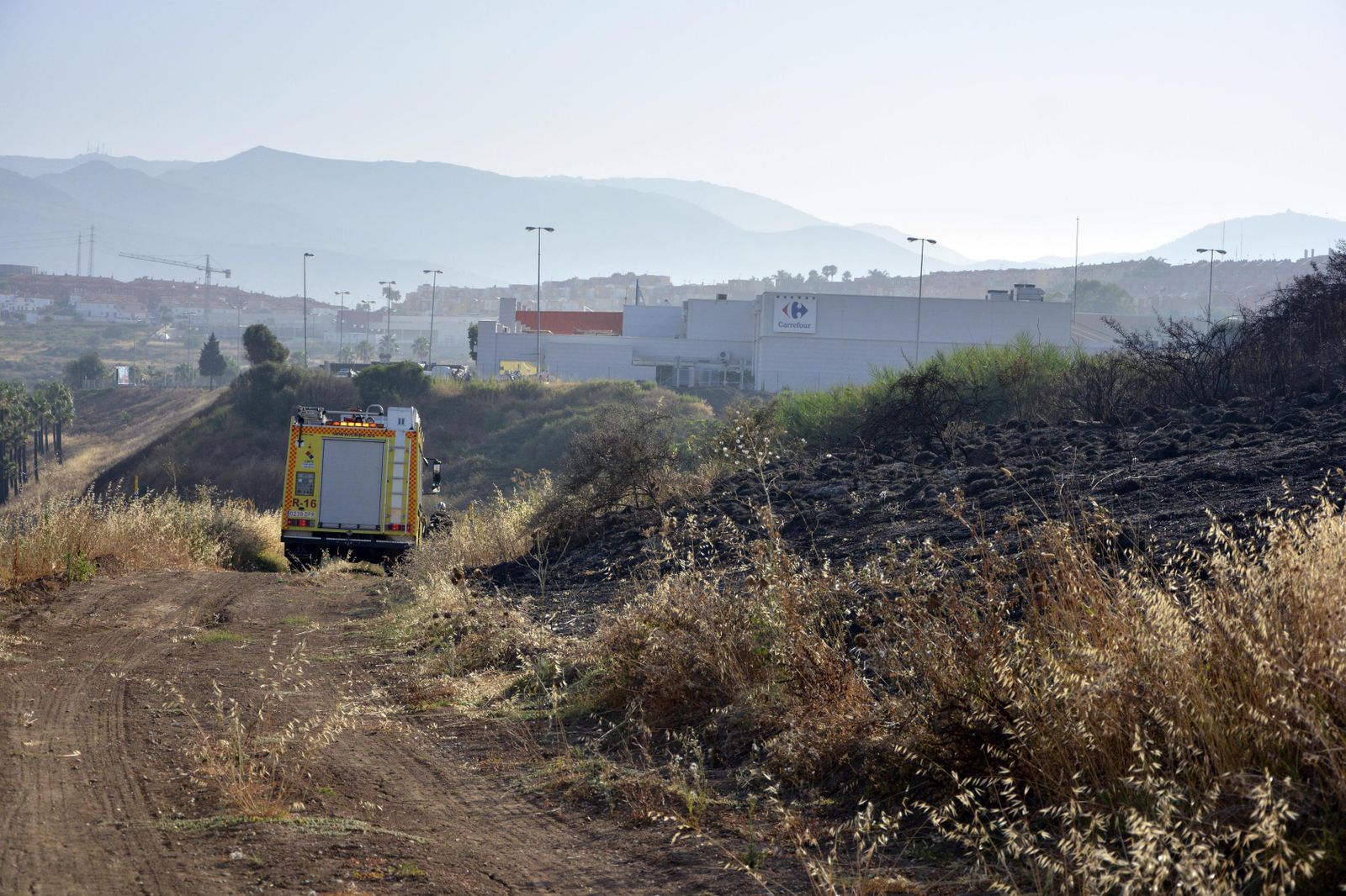 Un camión de bomberos, junto a parte de la zona quemada.