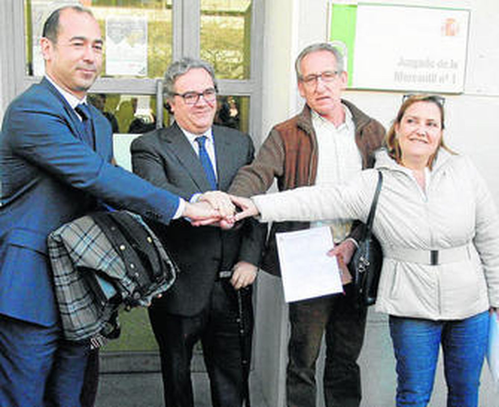 Los firmantes estrechan las manos tras la firma del documento en el Juzgado.