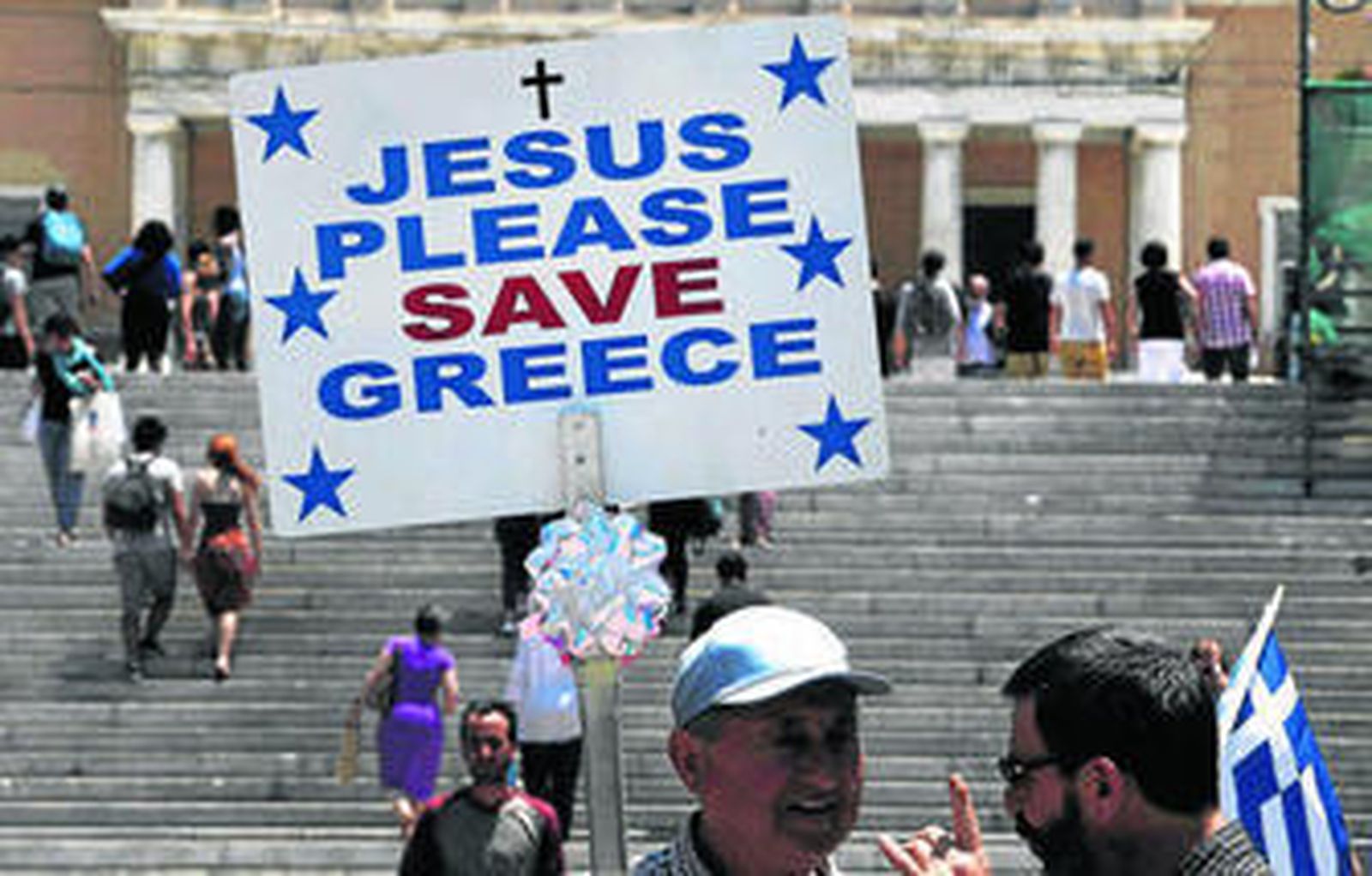 Un hombre sostenía ayer una pancarta en la que se lee: "Jesús, por favor salva a Grecia", en la plaza Syntagma de Atenas.