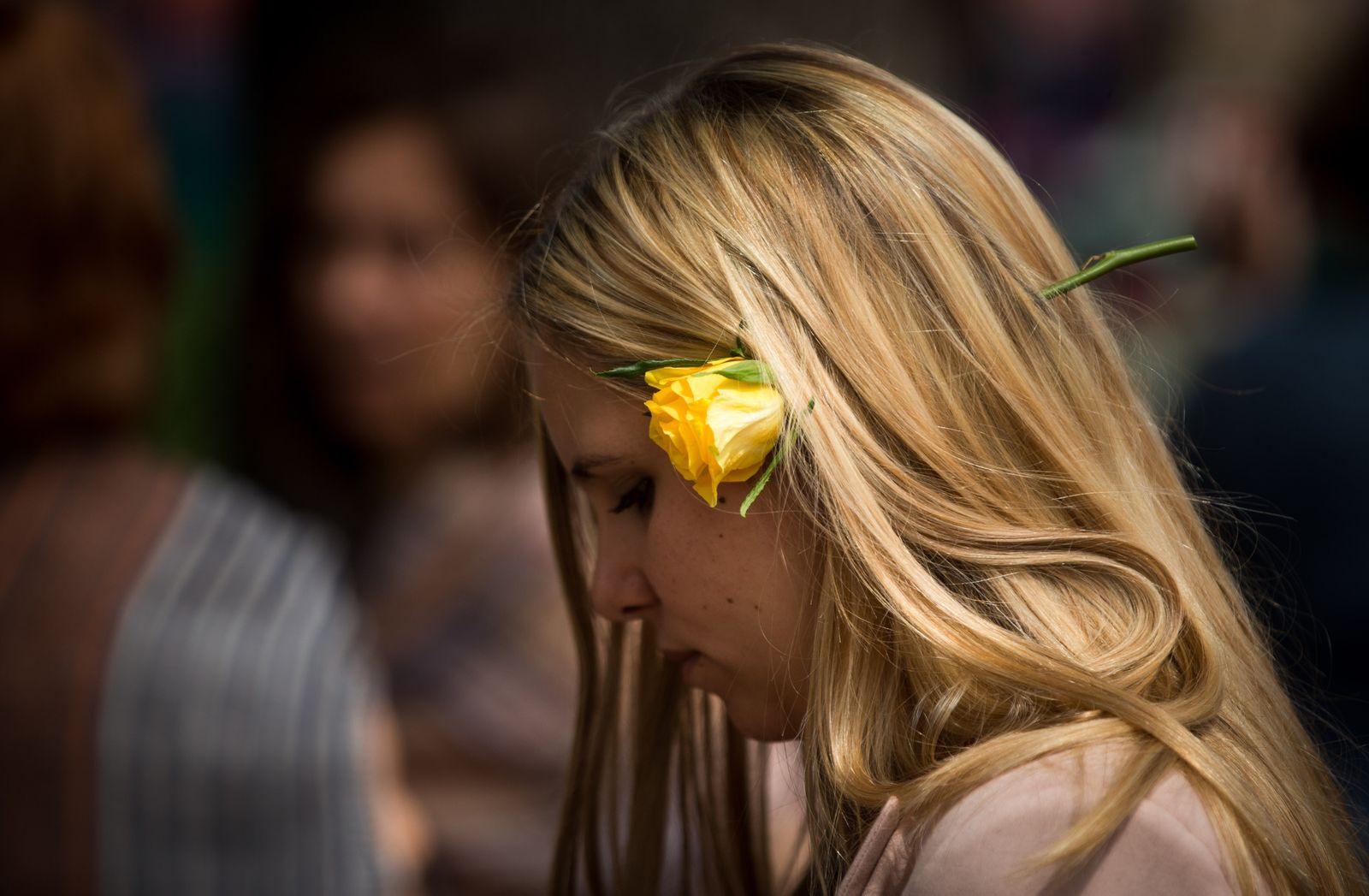 Una joven pasea con una rosa amarilla.
