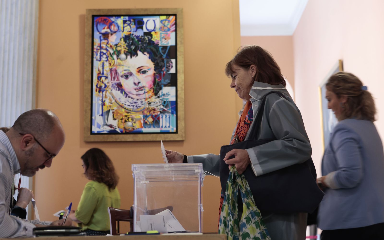 Una mujer deposita su voto en una mesa electoral del Ayuntamiento de Sevilla.