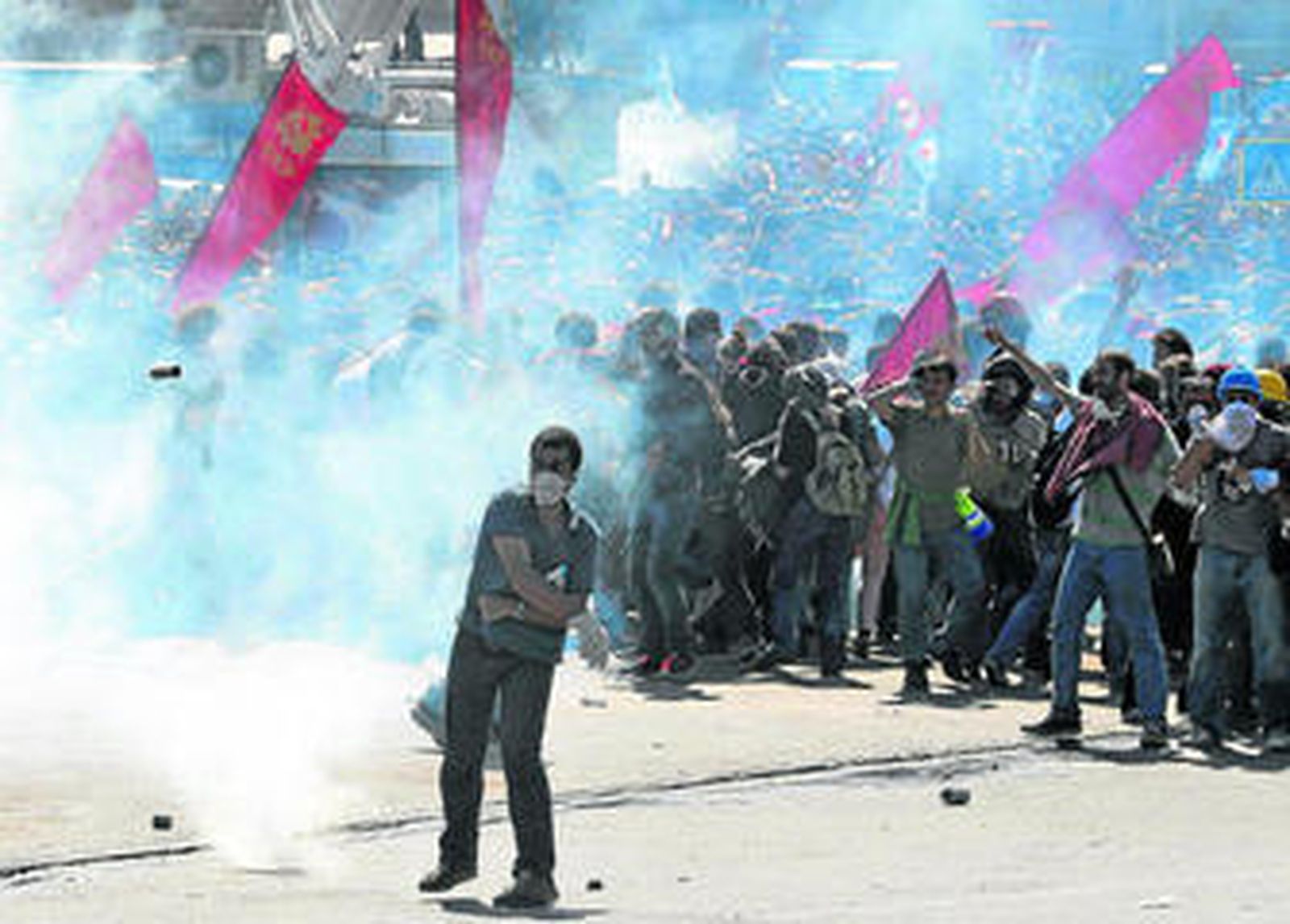 Un manifestante devuelve un bote de gas lacrimógeno lanzado por la Policía.