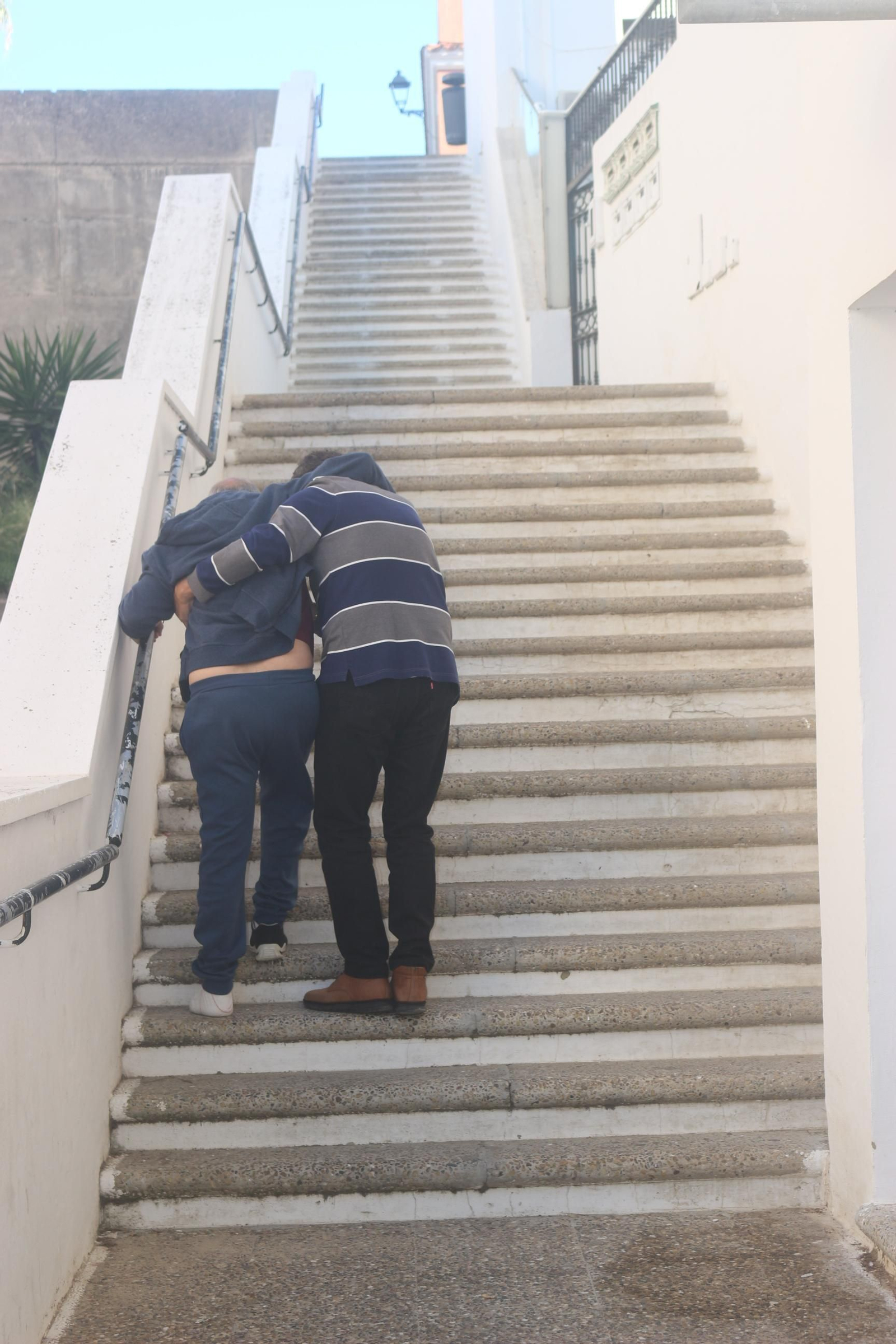 Manuel ayuda a su hermano Paco a subir la escalera de la calle