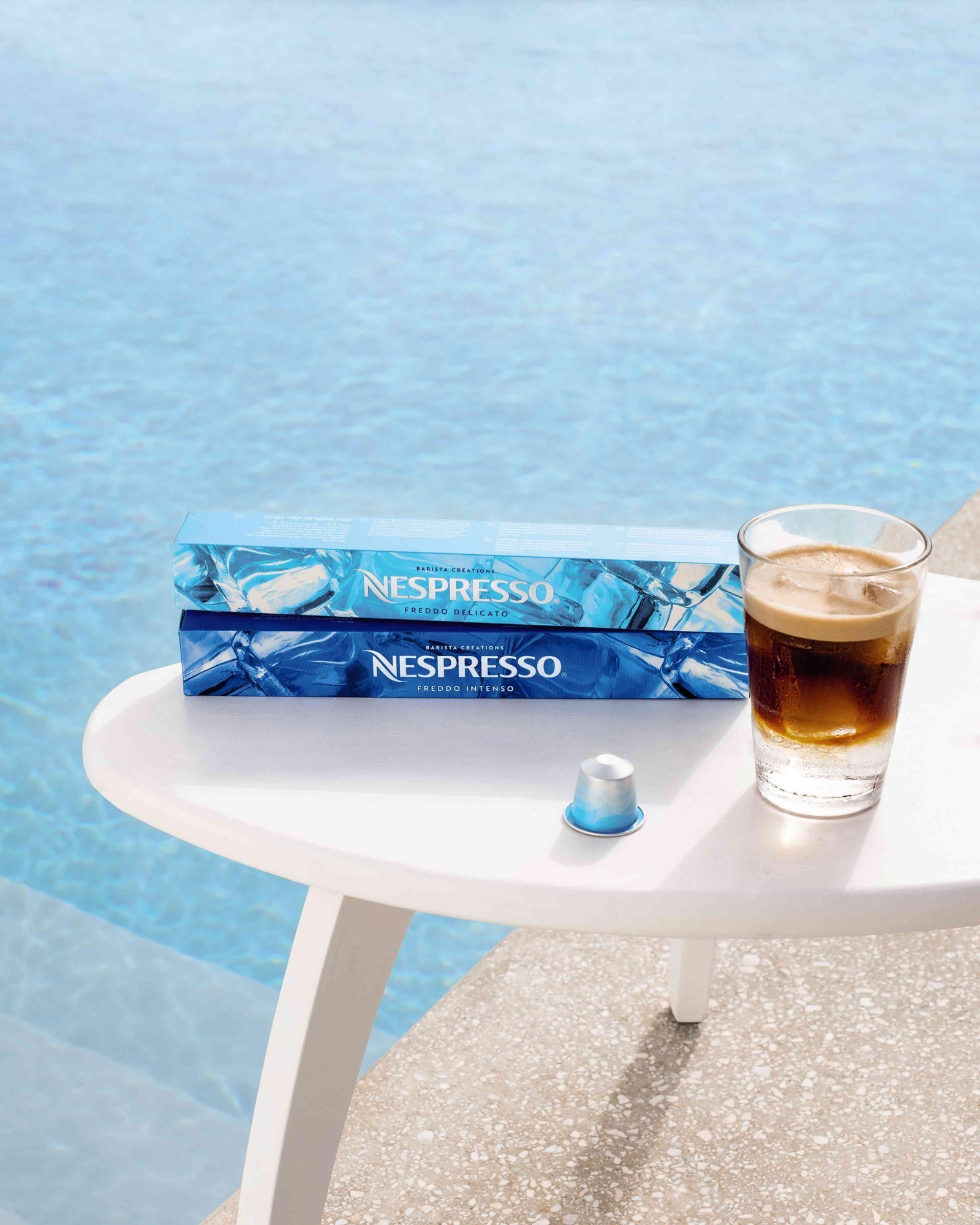 Pack de cápsulas junto a un café Nespresso 'Freddo Intenso'.