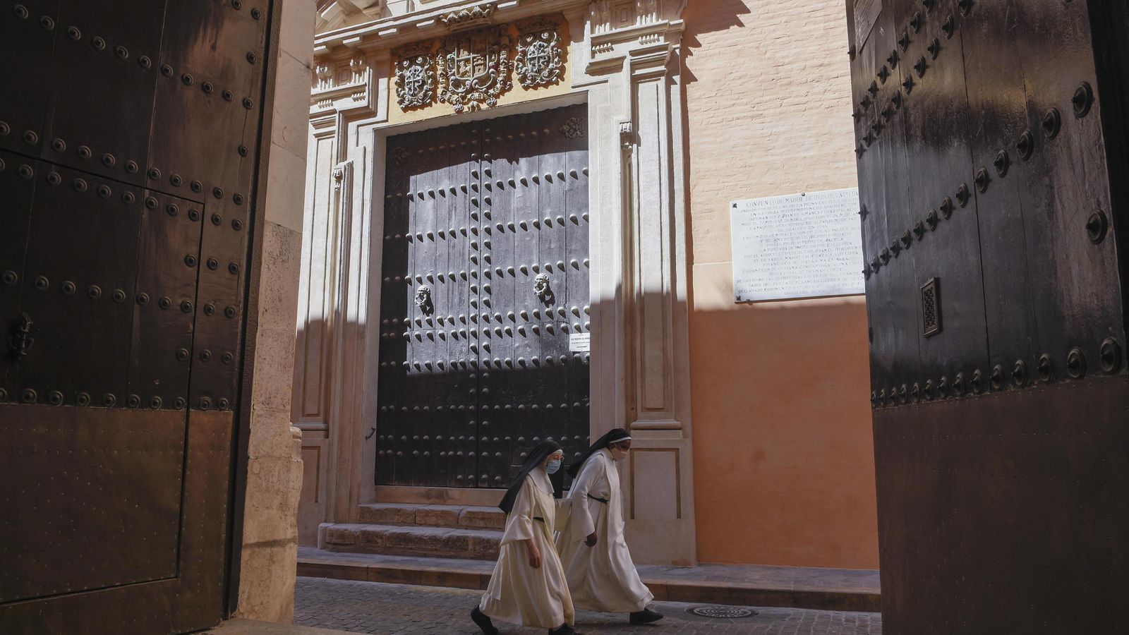 Las religiosas pasan ante la magnífica portada ya restaurada.