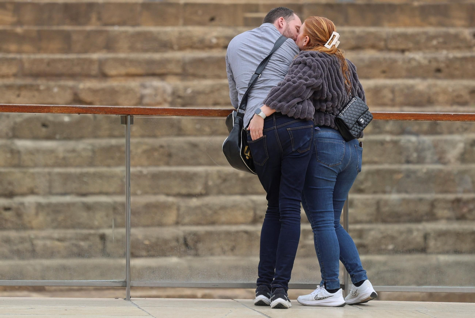 Una pareja se besa frente al Teatro Romano de Málaga. Una pareja se besa frente al Teatro Romano de Málaga.