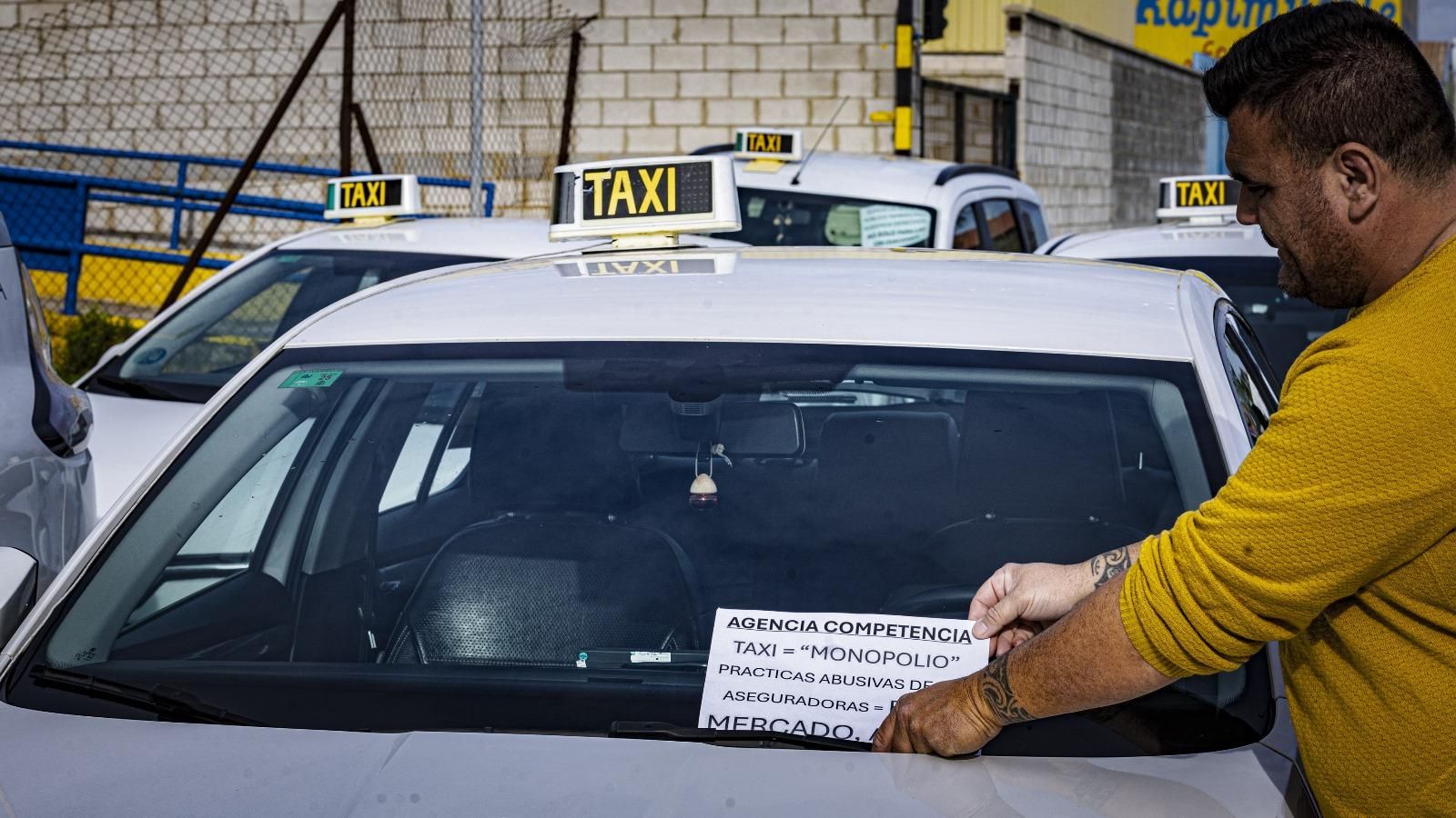 Un taxista coloca uno de los carteles de protesta en su vehículo.