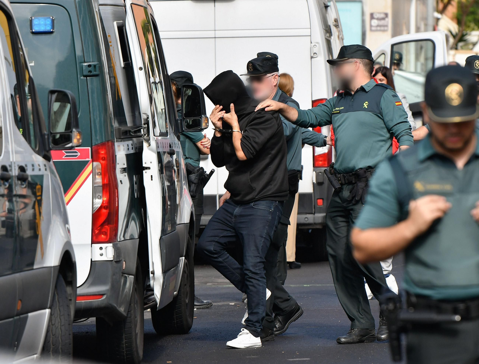 El policía nacional detenido es conducido a uno de los furgones de la Guardia Civil.