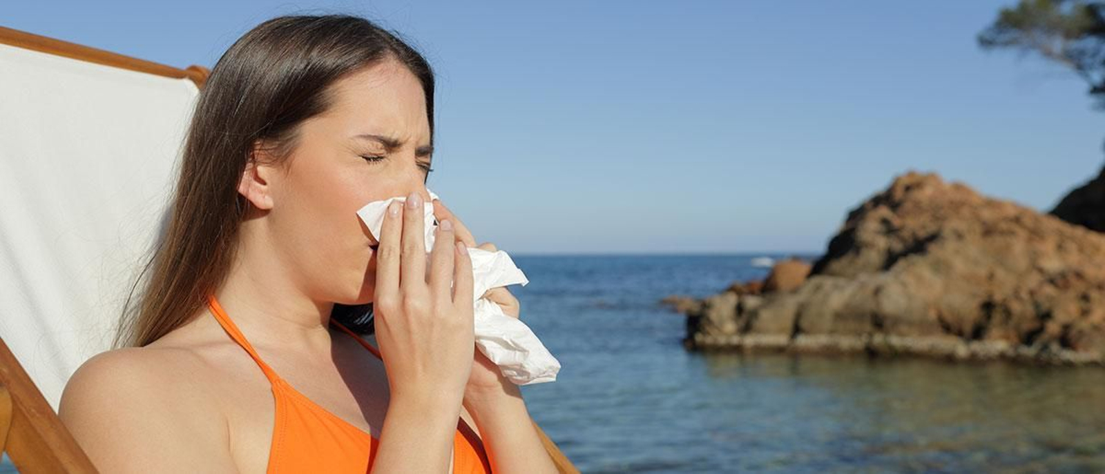Una mujer resfriada mientras disfruta de sus vacaciones