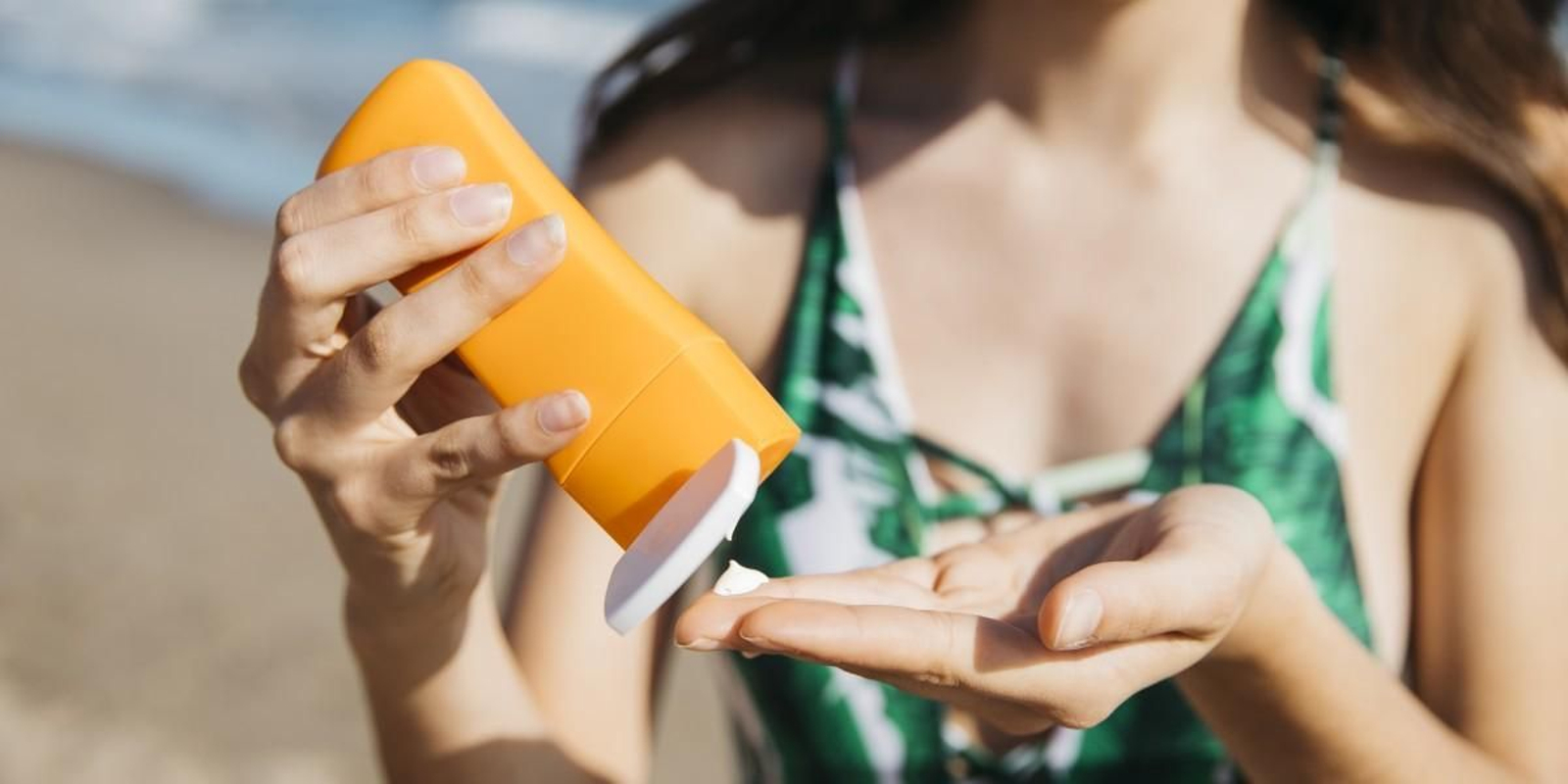 Un mujer se echa crema solar en la playa