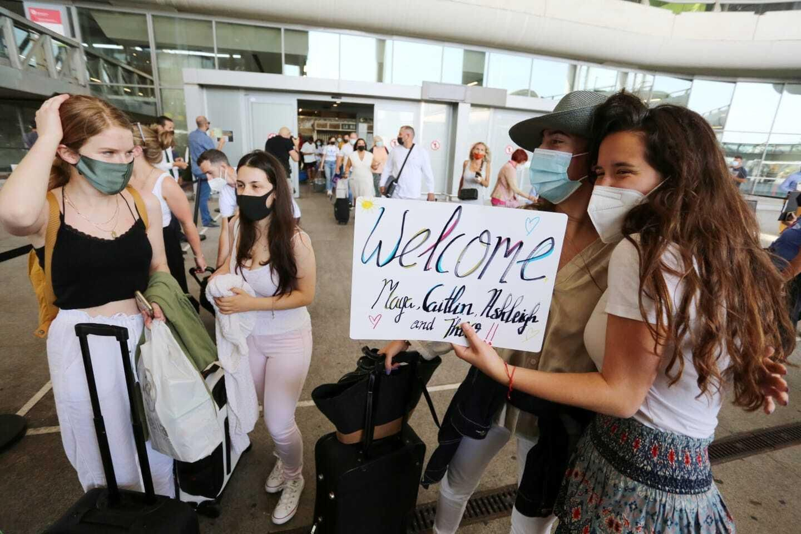 Una joven recibe a sus amigas con un cartel que reza "bienvenidas".