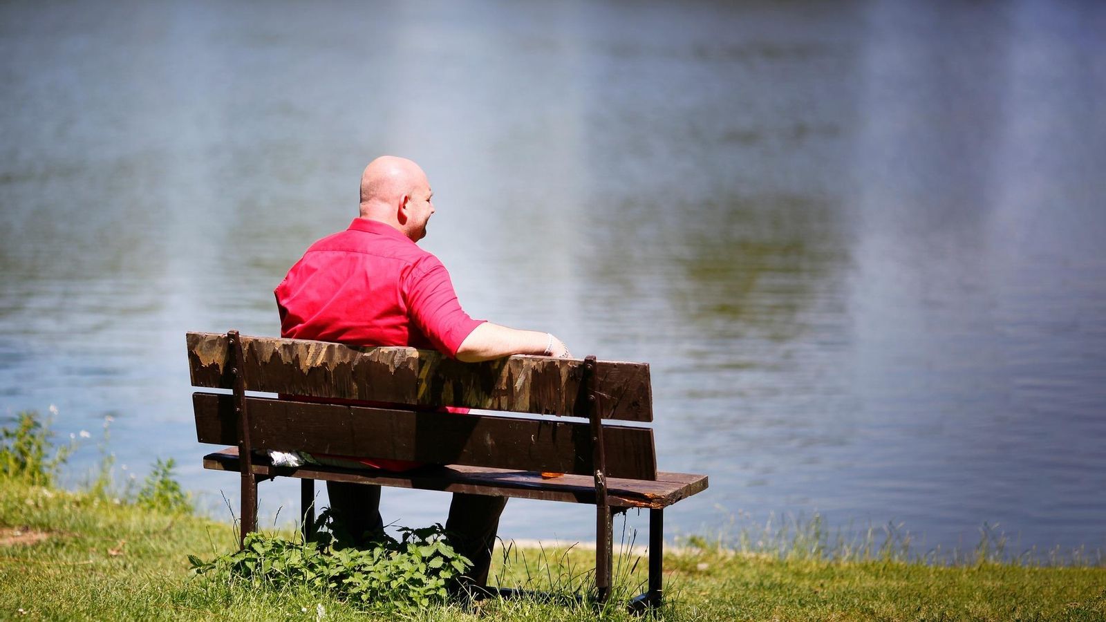 Un hombre sentado en un banco mirando el horizonte.