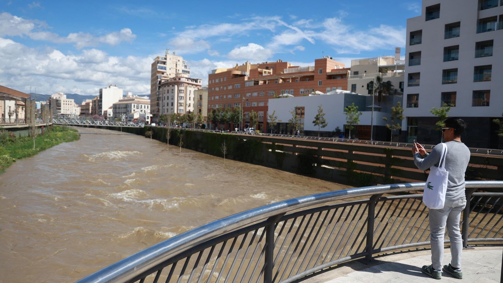 Turista hace una foto al Guadalmedina cargado de agua.