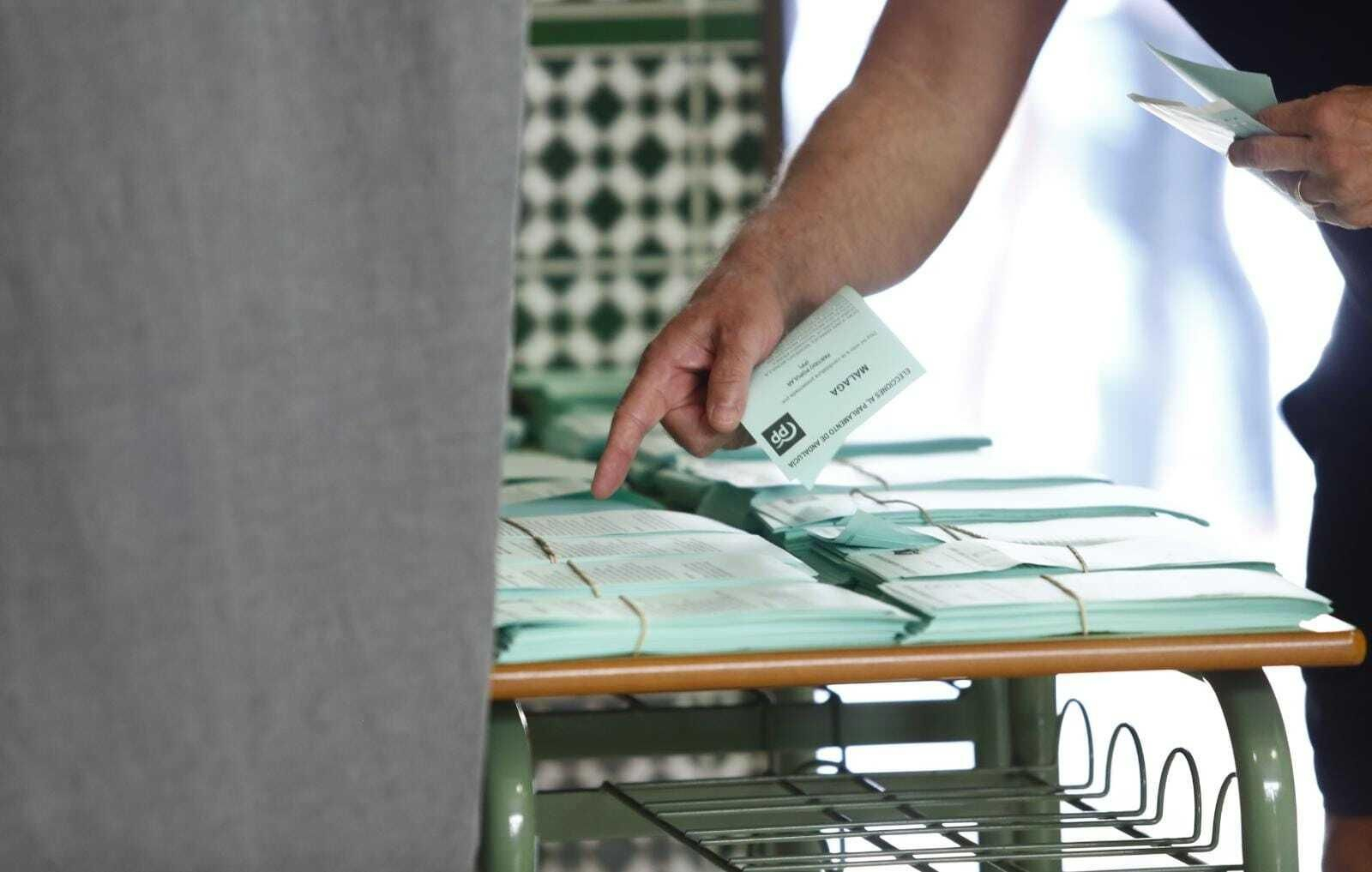 Una persona busca entre distintas papeletas en un colegio electoral.