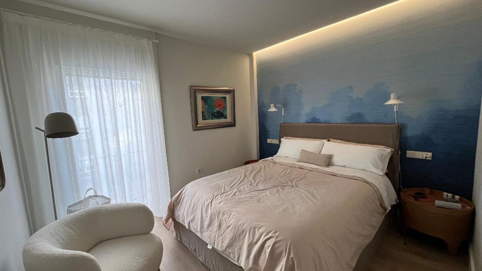 Dormitorio principal con una pared revestida con un papel seda cambiante de la firma Etilis.