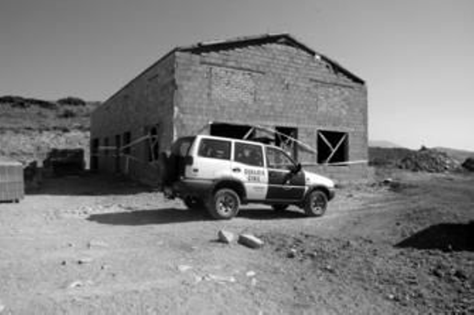 El vehículo de la Guardia Civil, aparcado junto a la nave precintada.