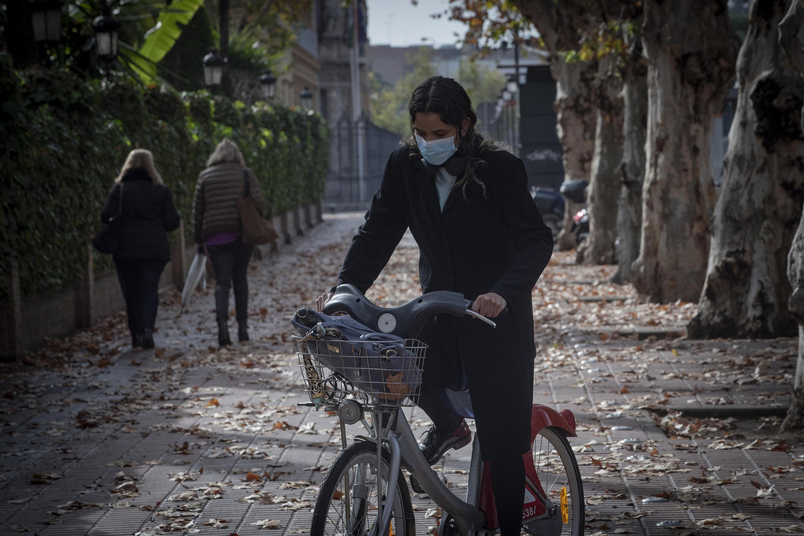 Un hombre pasea con su bicicleta por el centro de Sevilla.