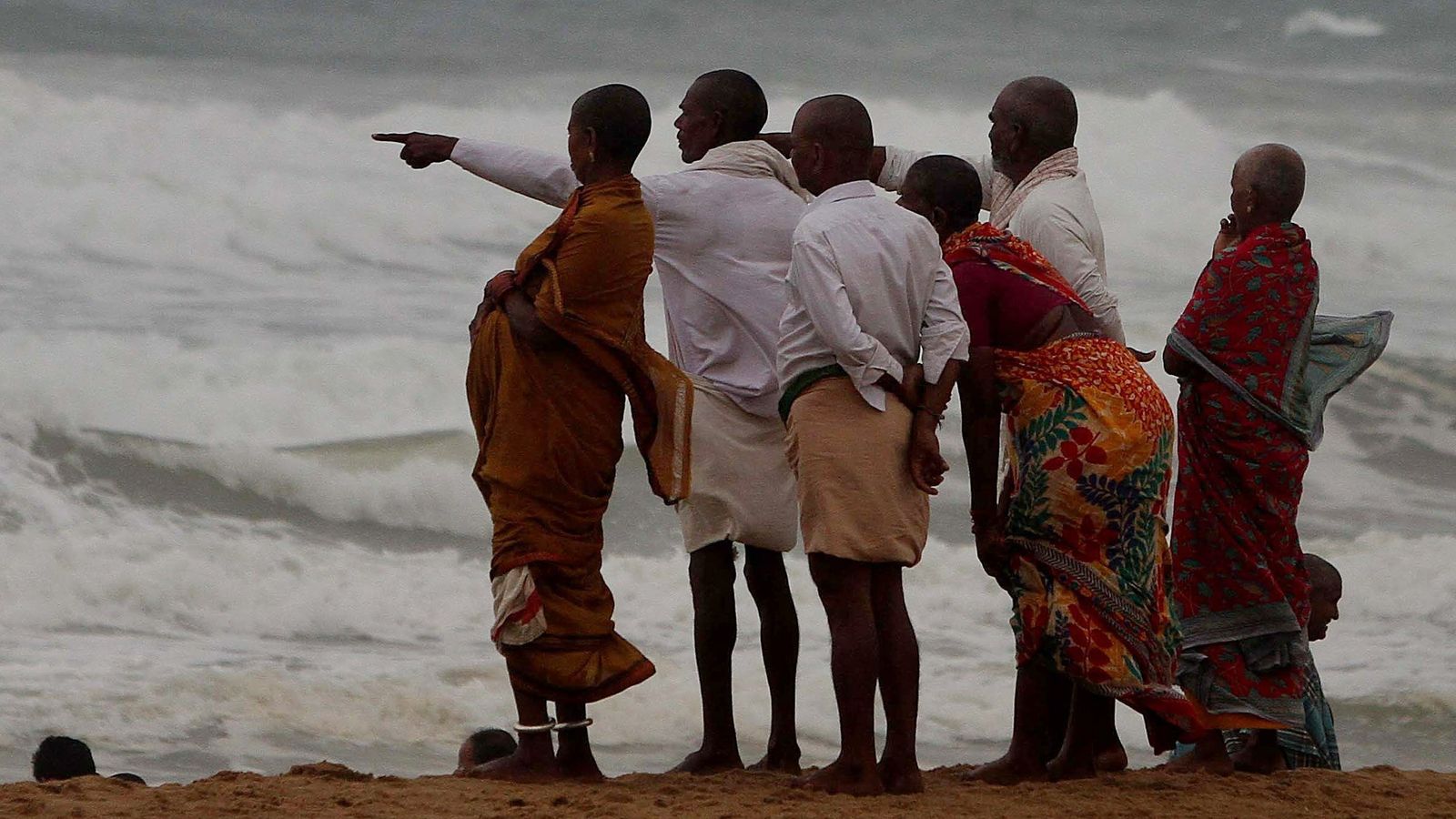 Varias personas contemplan en oleaje en el distrito de Puri, en la India.