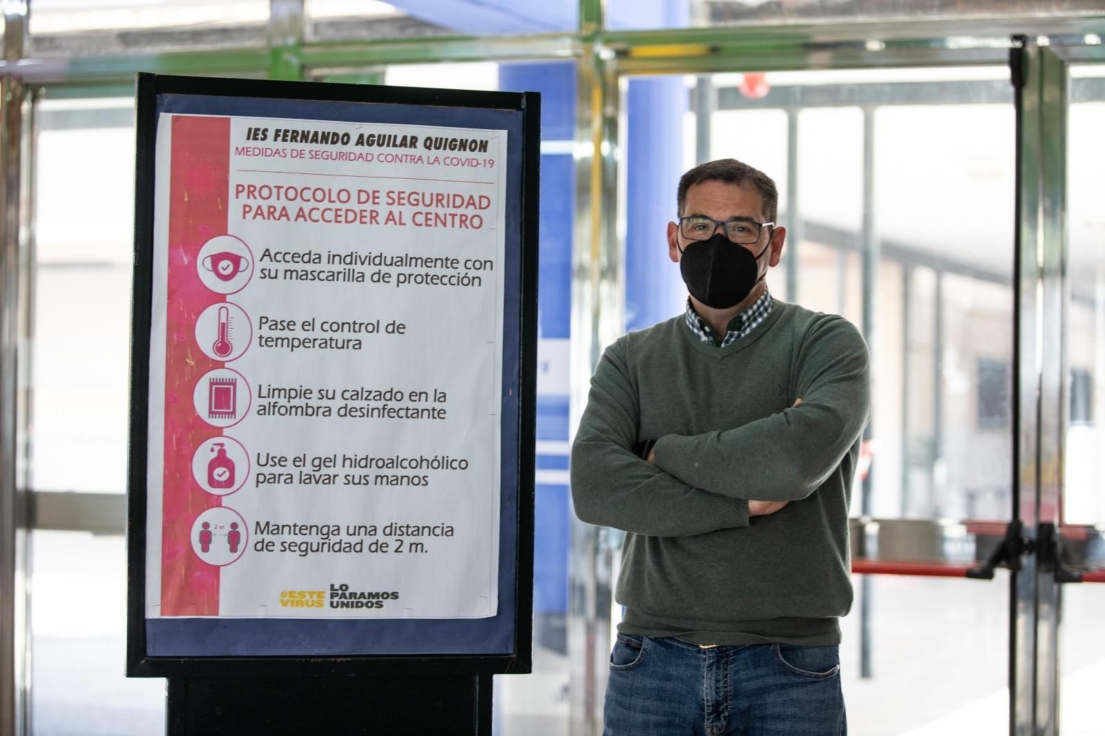 Pedro Fernández, coordinador covid del IES Fernando Aguilar Quignon de Cádiz, junto a un cartel con las medidas adoptadas en este centro.