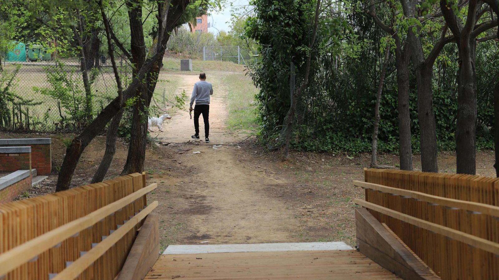 Un joven pasa por la apertura en la red metálica.