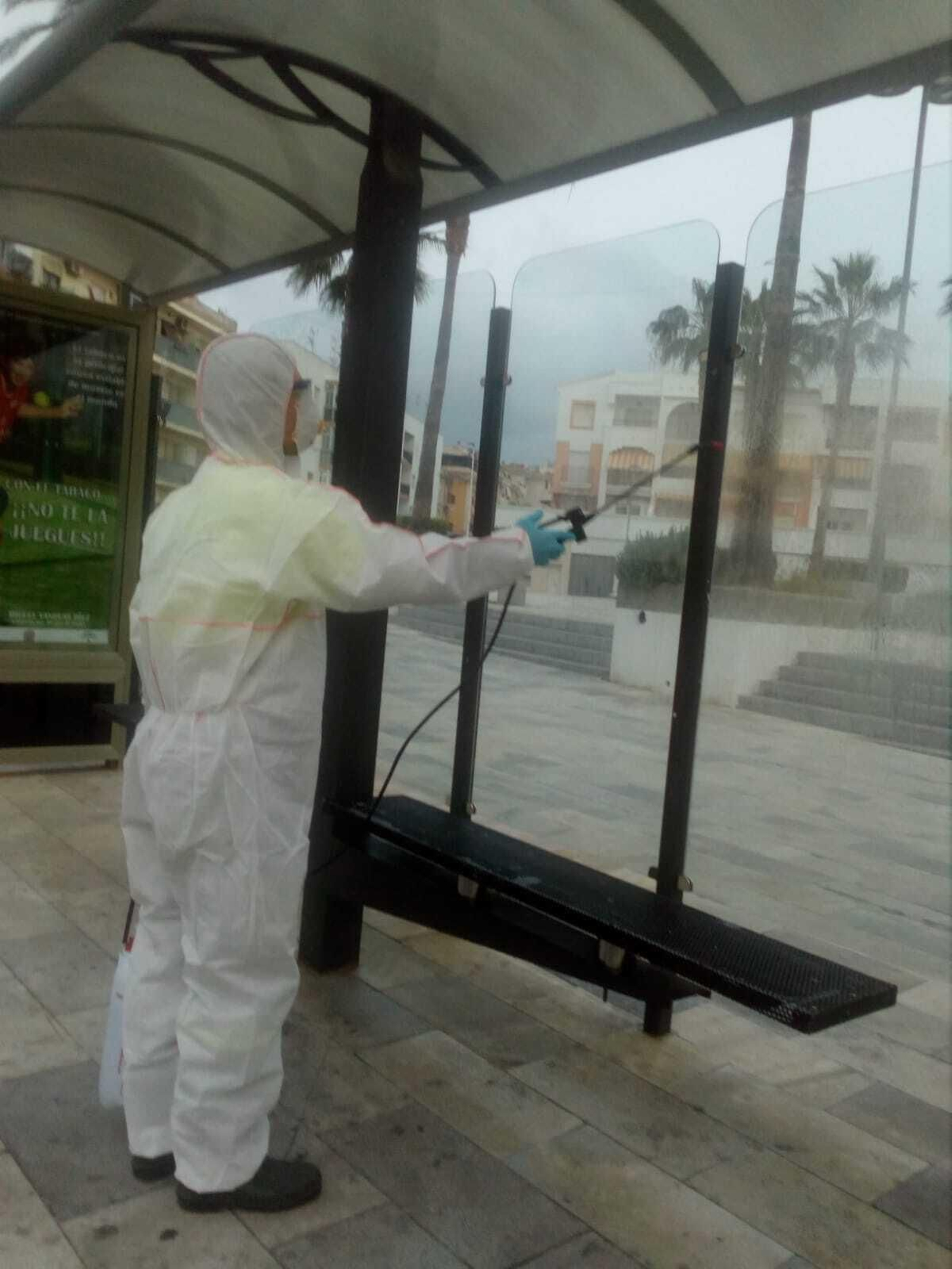 Labores de desinfección ante el coronavirus en una parada de autobús en Salobreña.