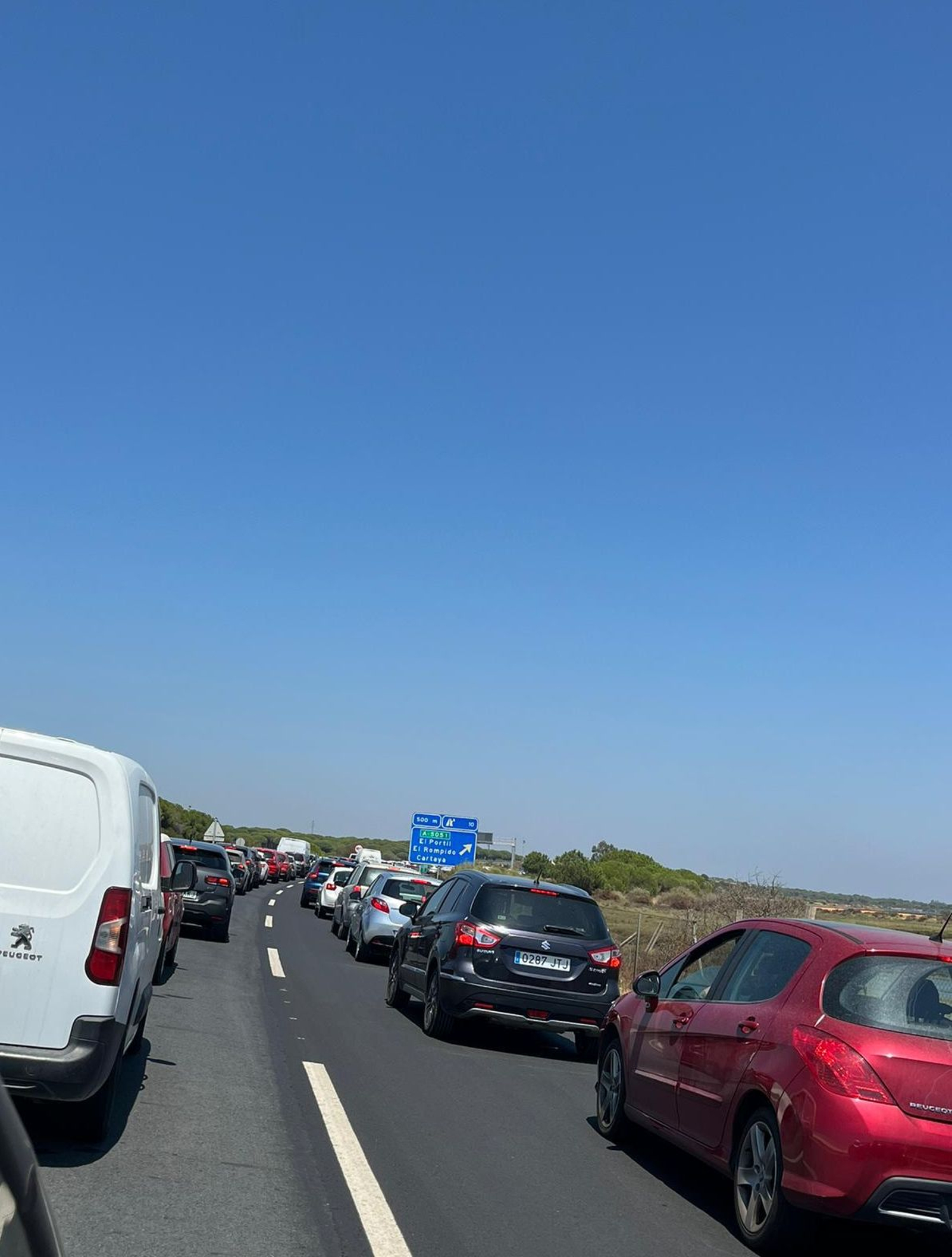 Una larga hilera de vehículos aguarda en la carretera Punta Umbría-Huelva. Una larga hilera de vehículos aguarda en la carretera Punta Umbría-Huelva.