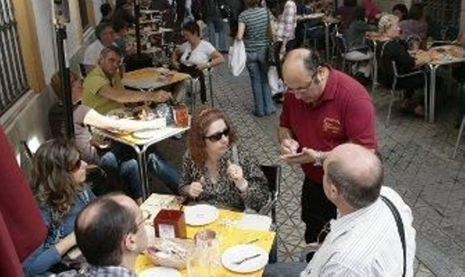 Un camarero atiende a unos clientes en un velador del centro. /J.C. Muñoz