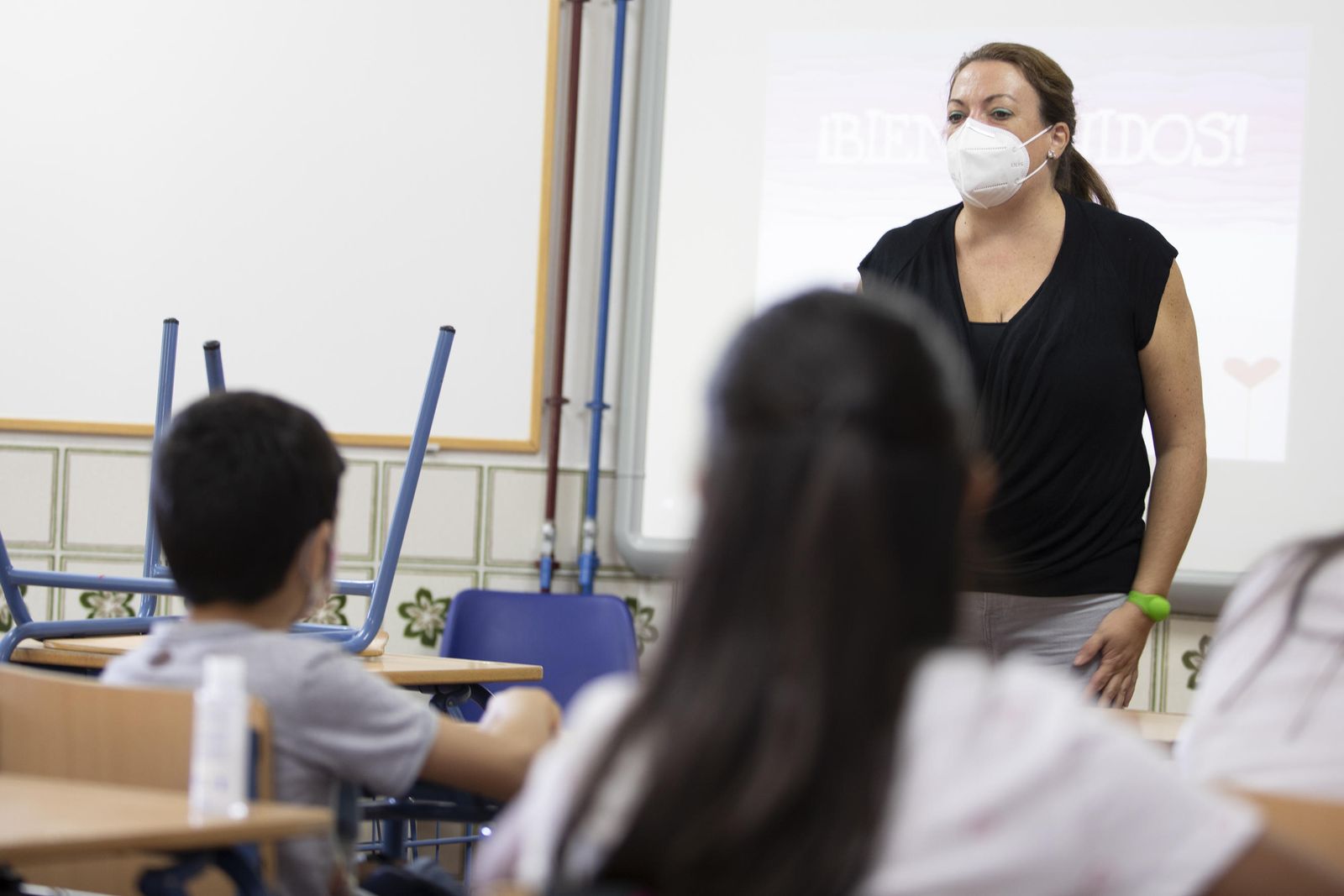 Una profesora imparte clase con mascarilla.