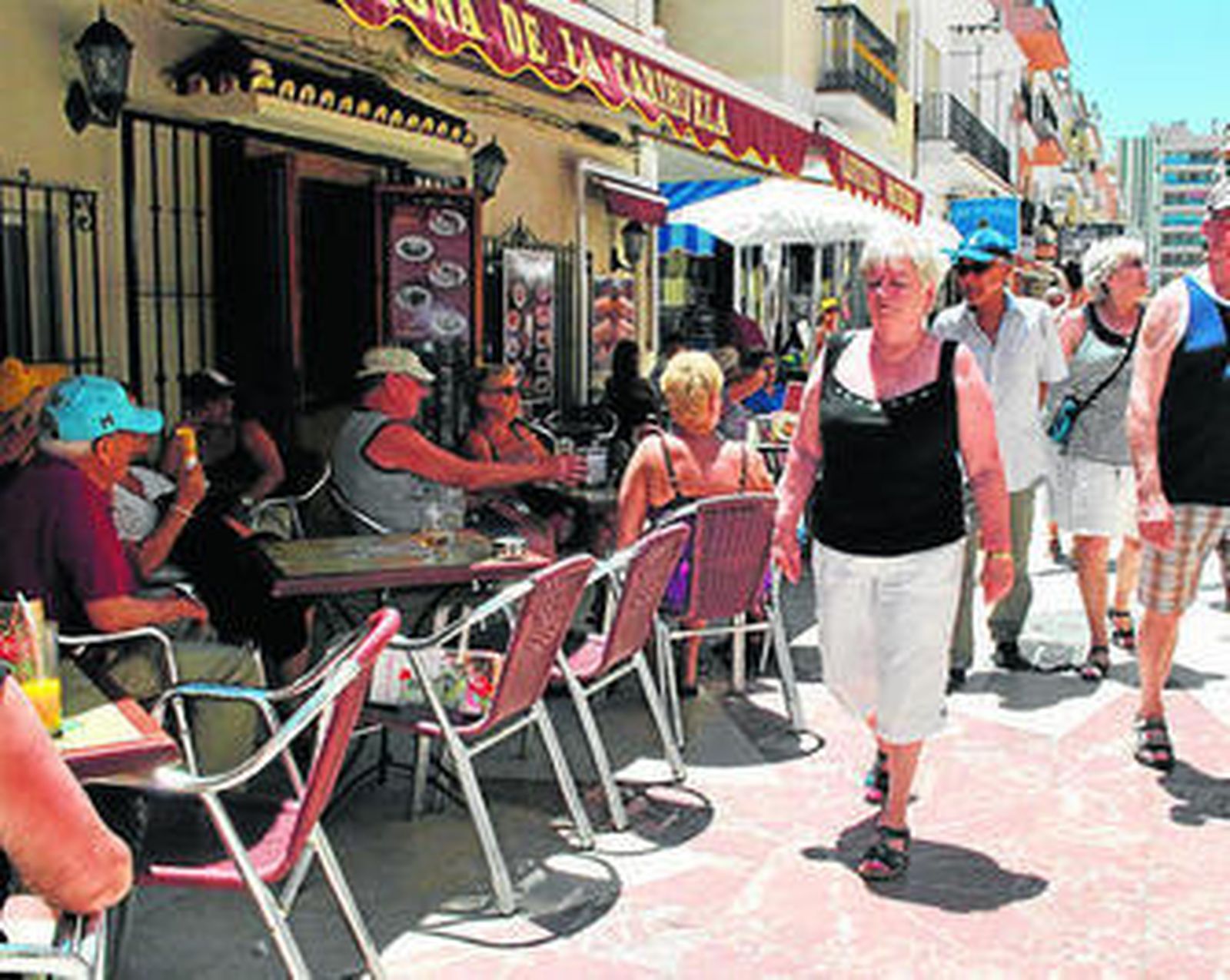 Extranjeros pasean por una calle de la costa occidental.