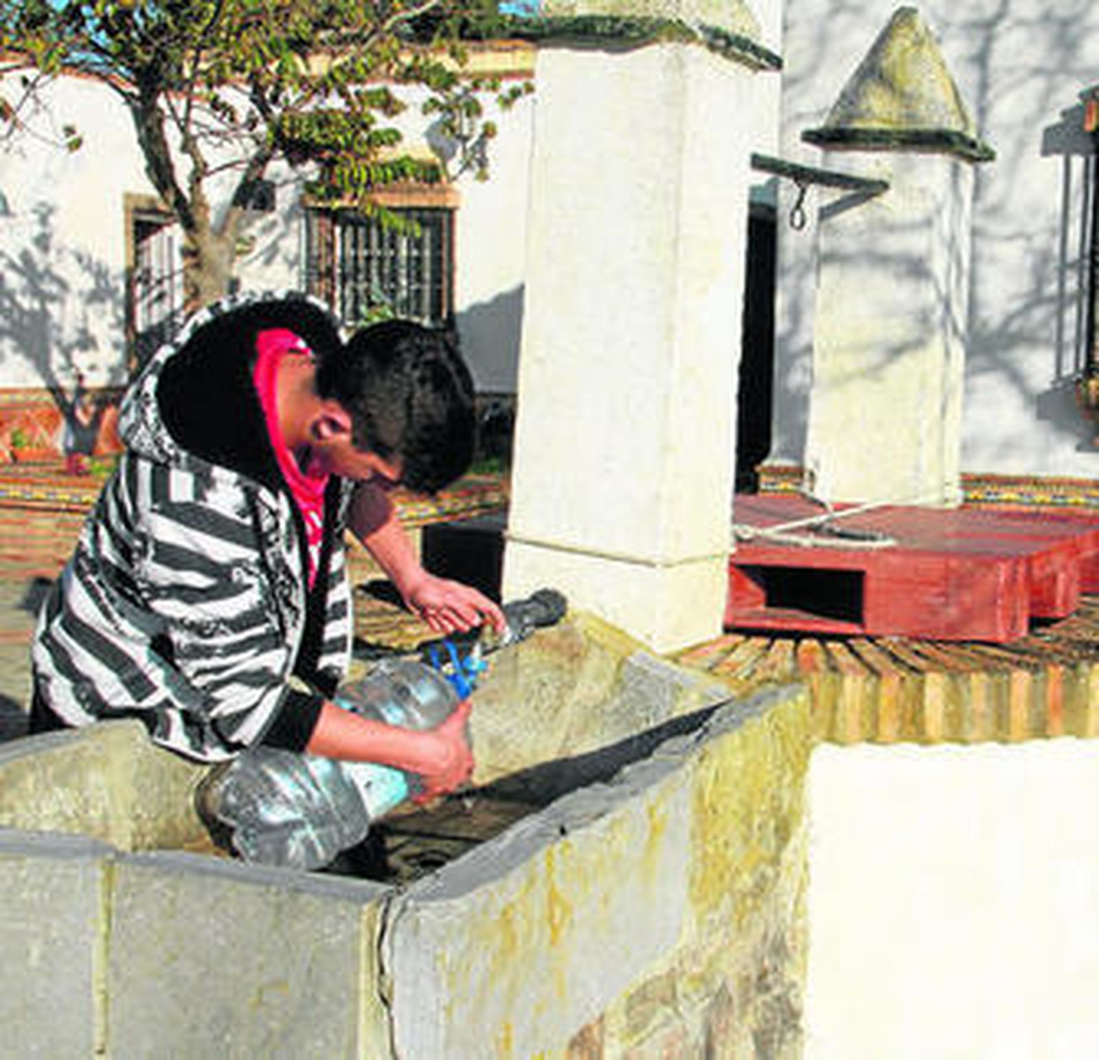 Un joven saca agua de un pozo particular de vivienda irregular en Conil