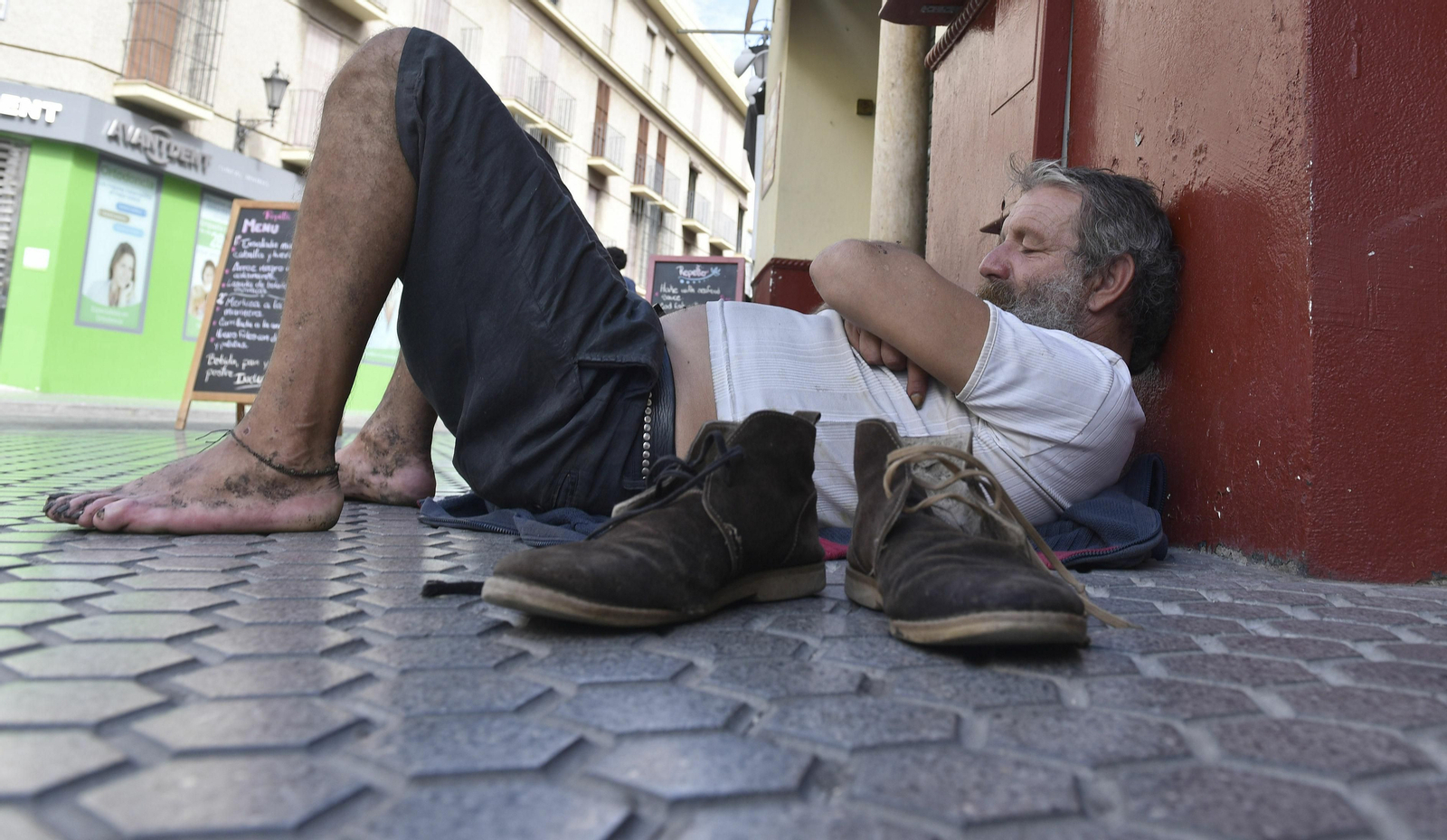 Un hombre descansa en el suelo de una céntrica calle de la ciudad.