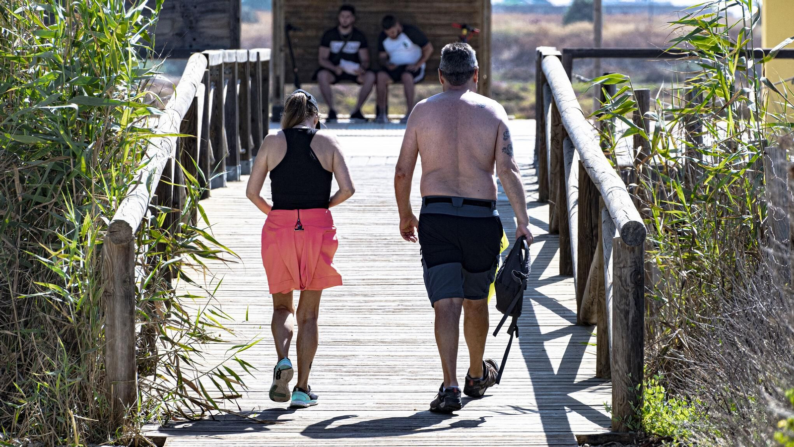 Dos usuarios de la playa de Camposoto, de salida por una de las pasarelas.