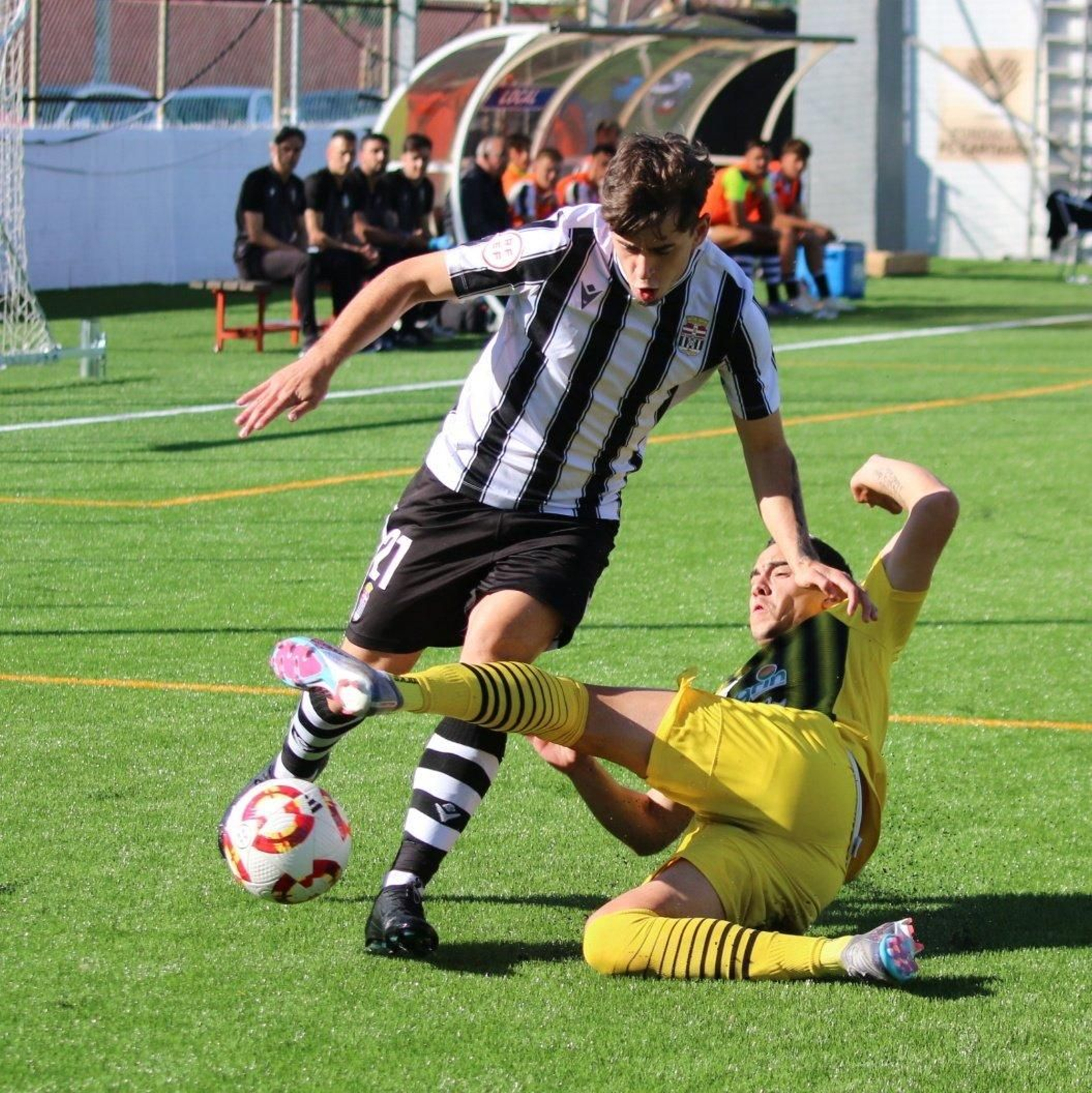 Un jugador del conjunto almeriense trata de cortar el balón con una entrada a ras de suelo a un futbolista albinegro.