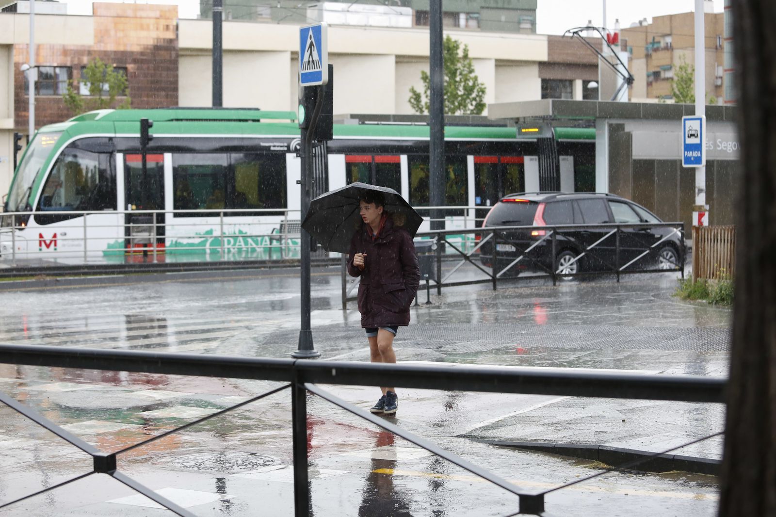 Una joven se resguarda de la tormenta en Granada.