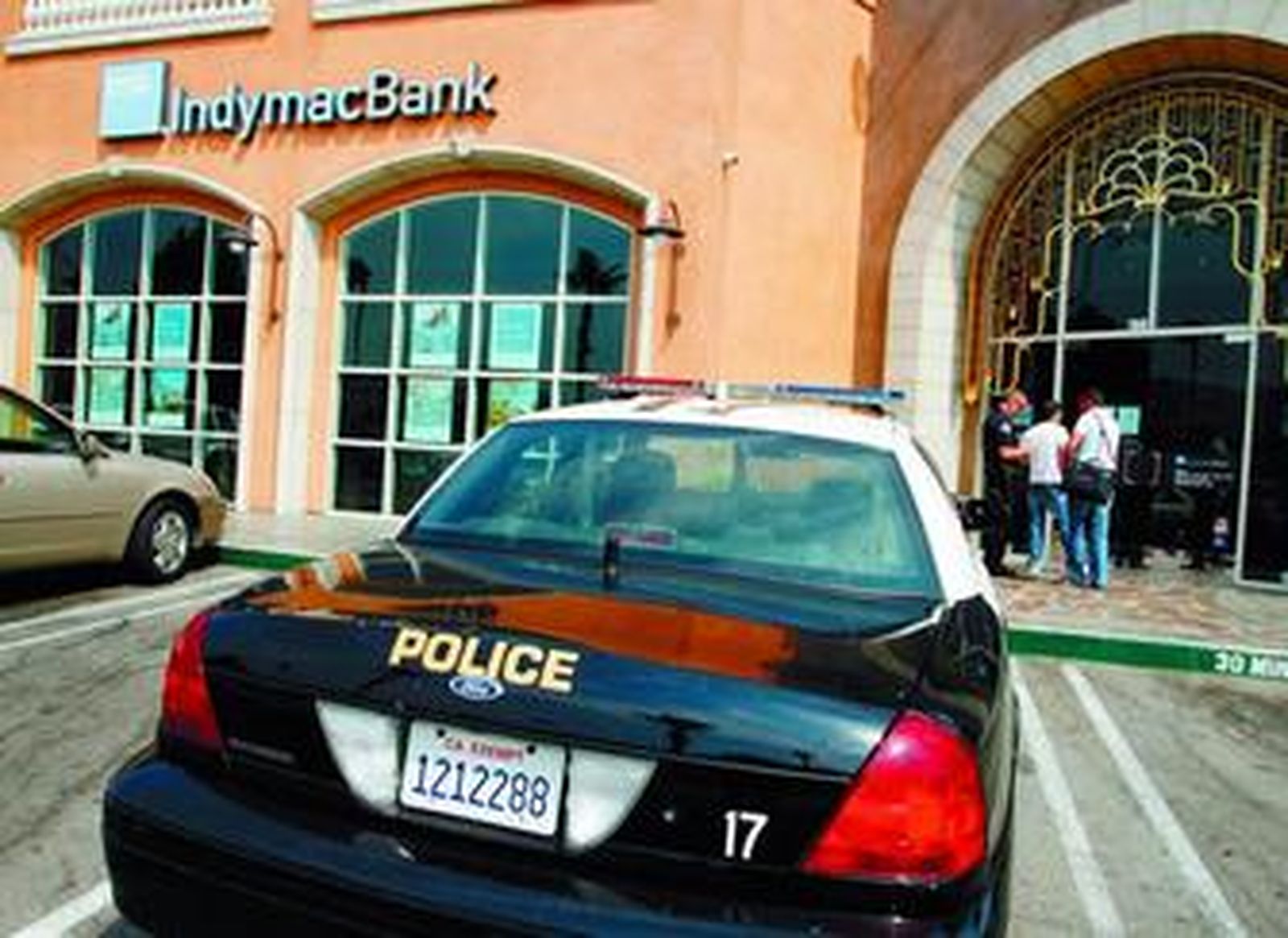 Clientes de Indymac conversan con un policía a las puerta de una oficina del banco en California.