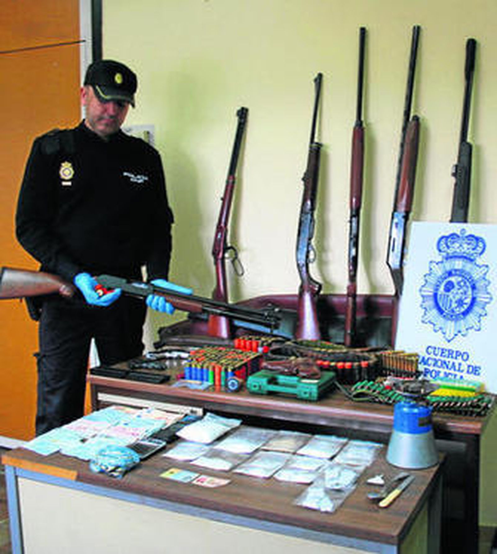 Un portavoz de la Policía muestra las armas, la munición, la droga y el dinero requisados.