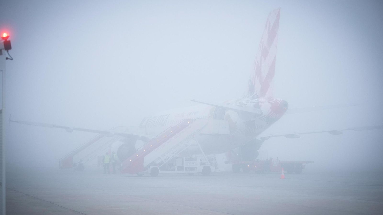 Un avión de Volotea estacionado en el aeropuerto de Granada bajo la densa niebla