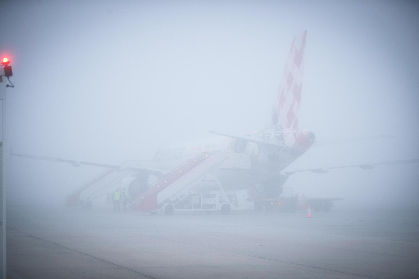 Un avión de Volotea estacionado en el aeropuerto de Granada bajo la densa niebla