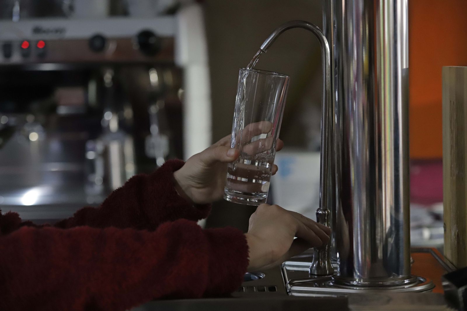 Una persona sirve agua desde un grifo.