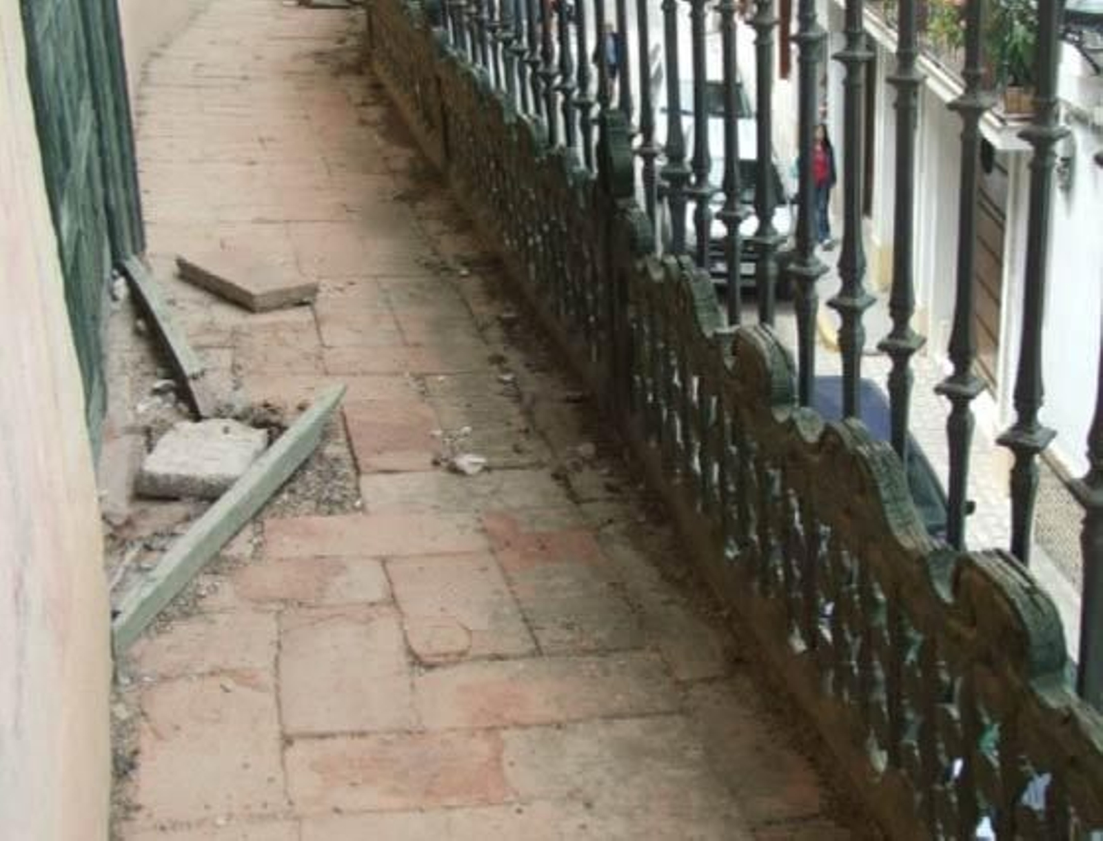 Imagen de un pasillo junto al balcón, con losetas y barrotes por el suelo.