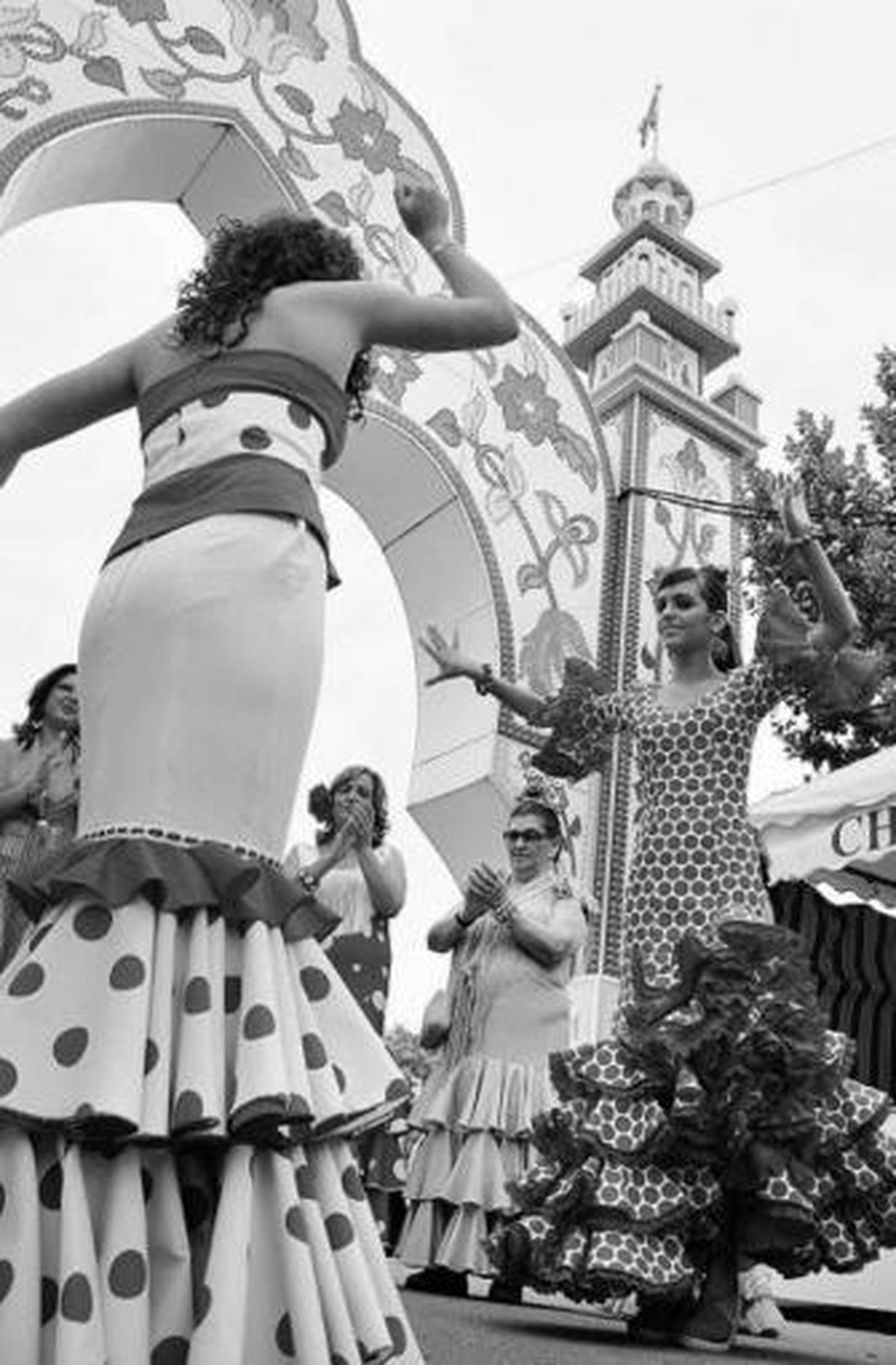 Jóvenes ecijanas bailando junto a la portada de su feria.