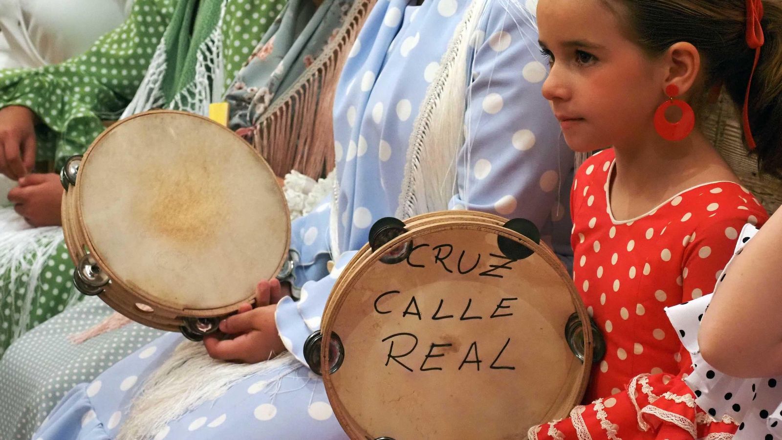 Una pequeña aprende la tradición en la Cruz de la Calle Real