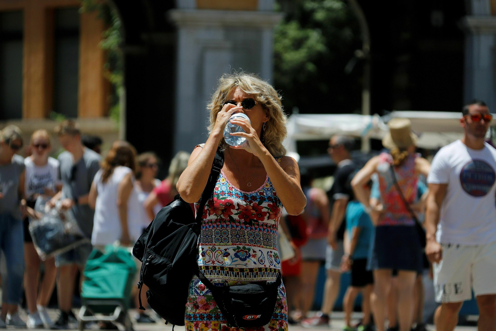 Un mujer se refresca bebiendo agua en la calle.