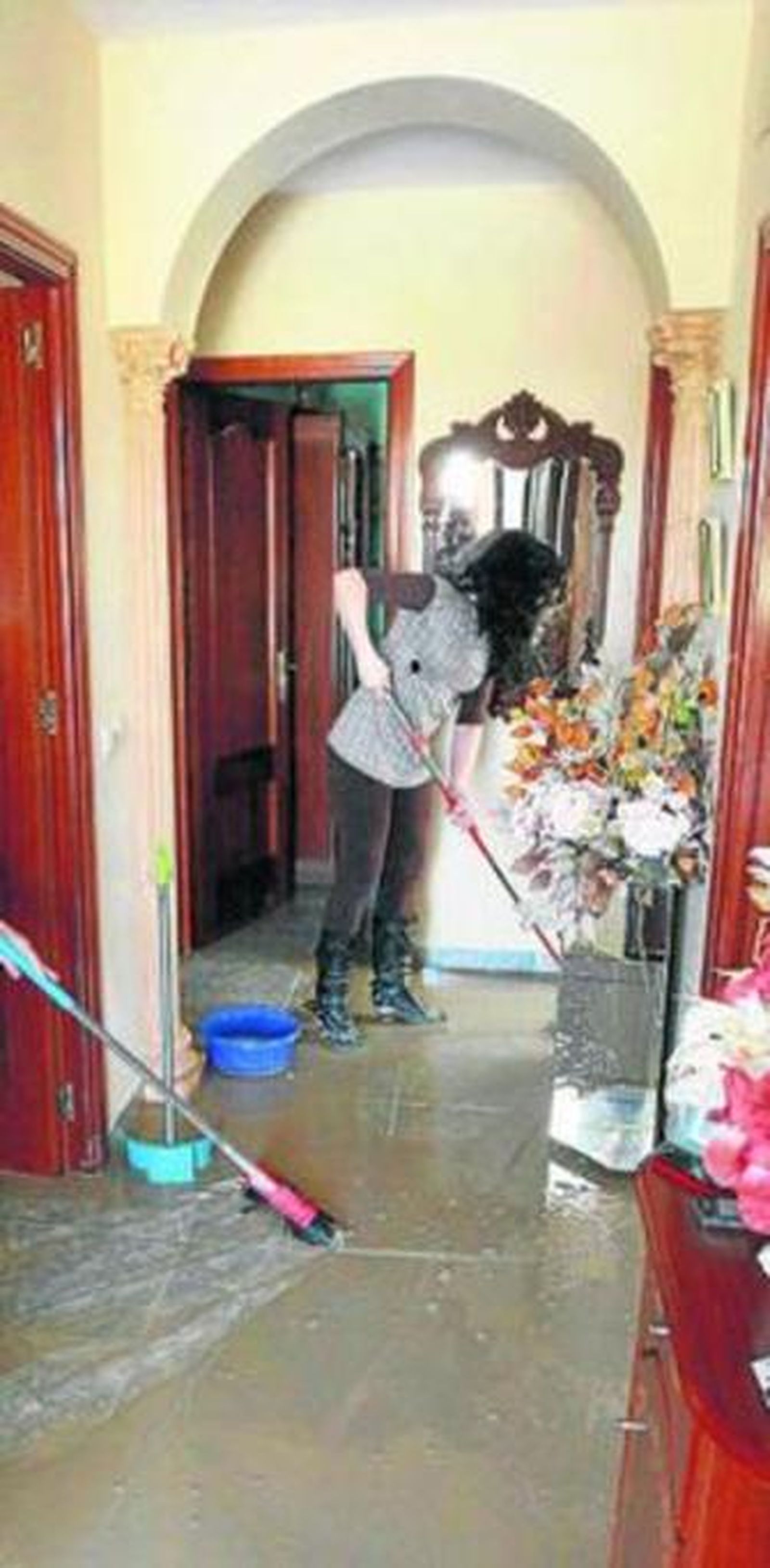 Dos mujeres sacan agua de una de las casas anegadas.